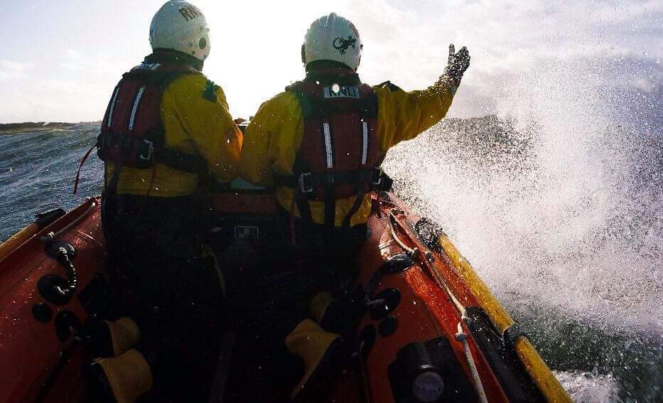 Two crew at front of boat pointing at casualty