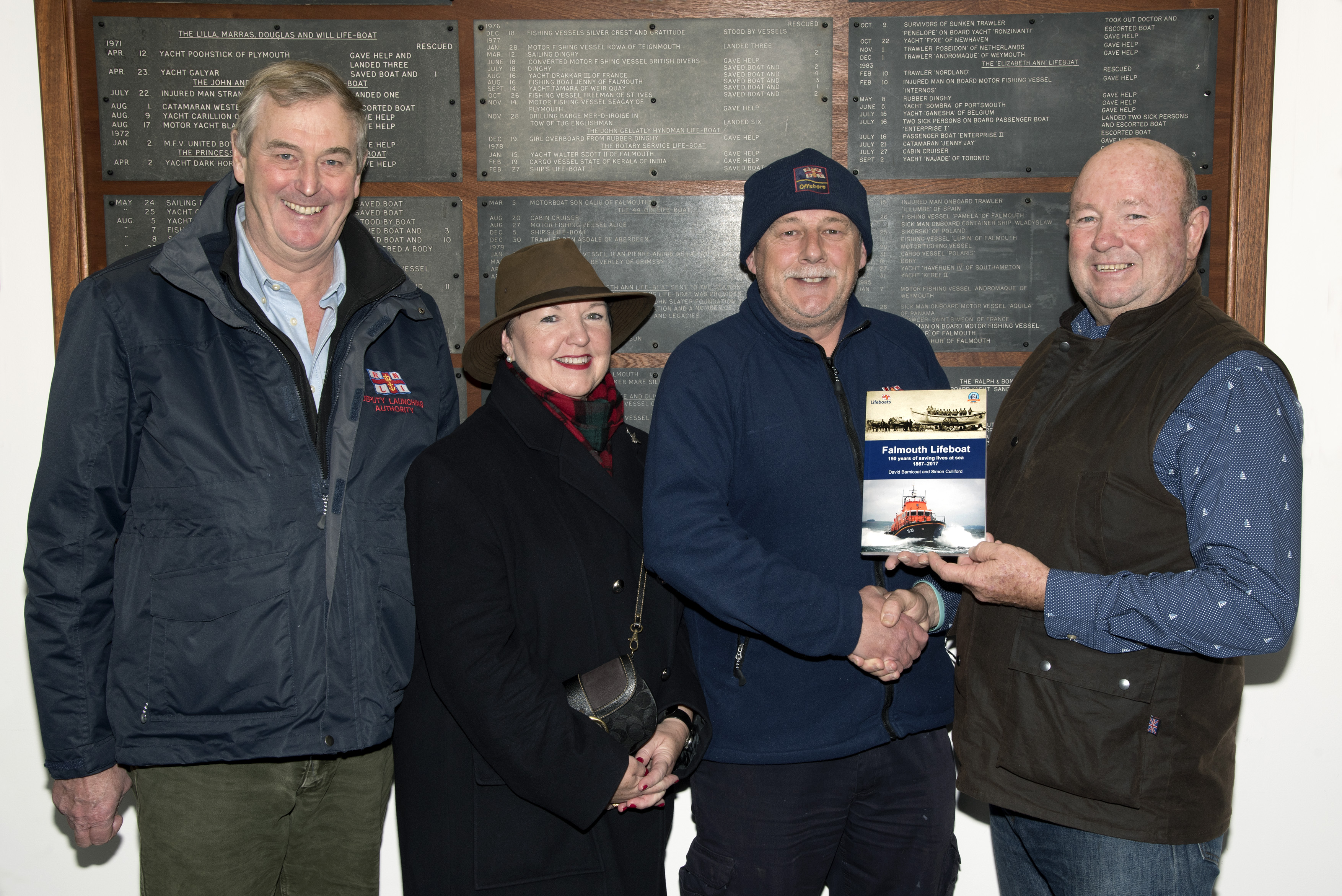 Falmouth RNLI Coxswain Jonathon Blakeston presenting Chris Lloyd with a signed copy of the station book produced in 2017 to commemorate the station’s 150th anniversary with Jane Lloyd and Lifeboat Operations Manager Nick Lewis to the left.