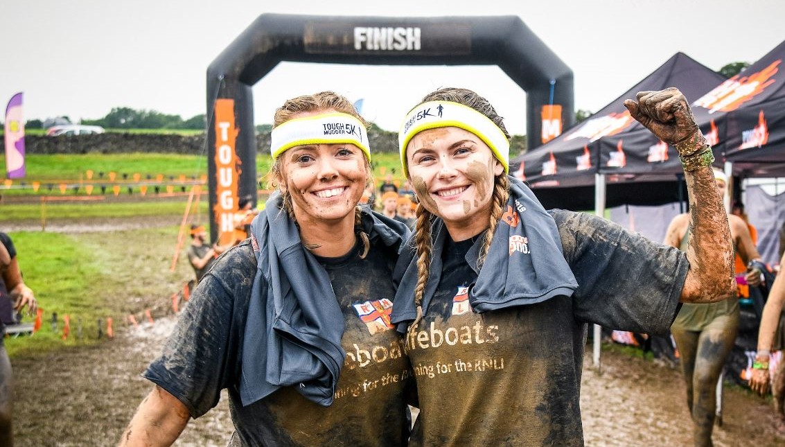 Two Haven team members celebrate running a Tough Mudder race for the RNLI