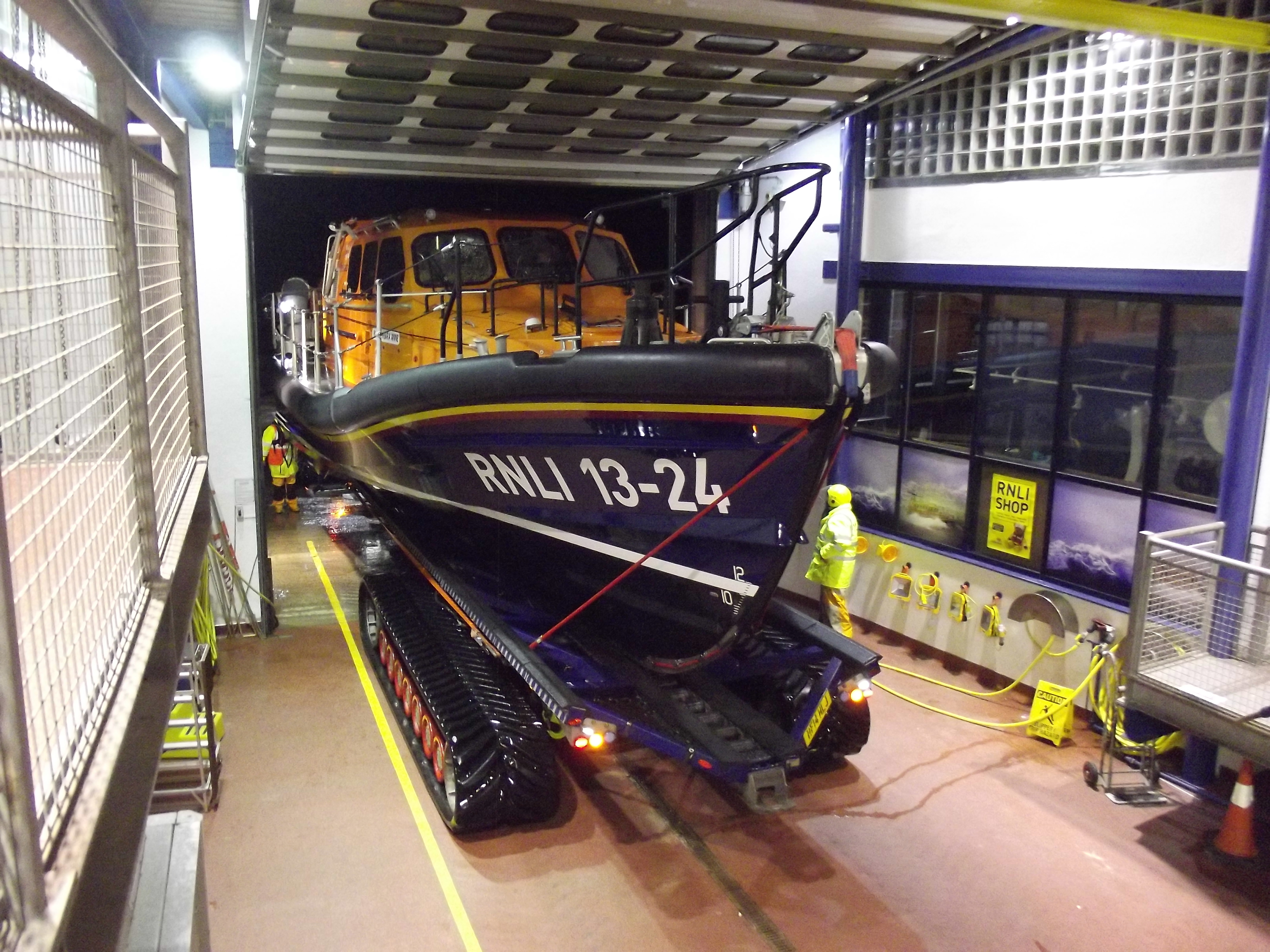 a lifeboat on a carriage is entering through the door of her boathouse