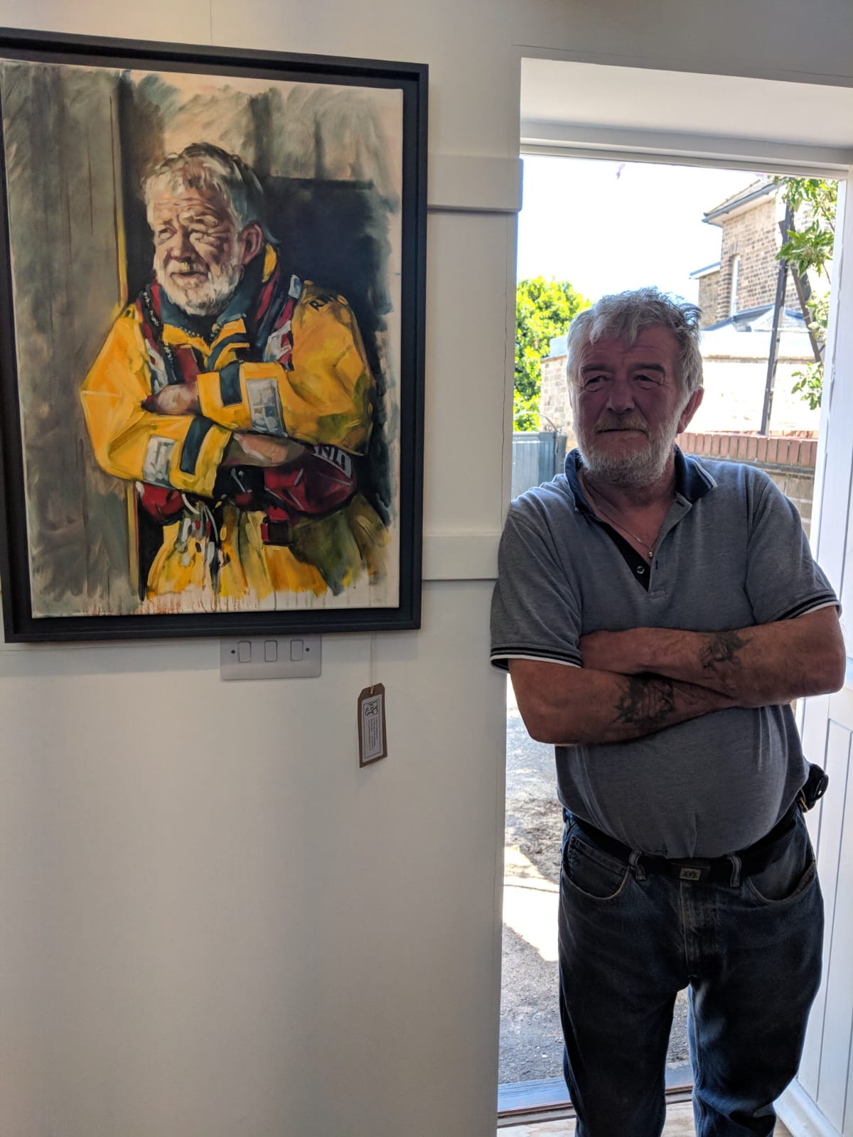 Mark Cable standing next to his portrait by David Gillingwater
