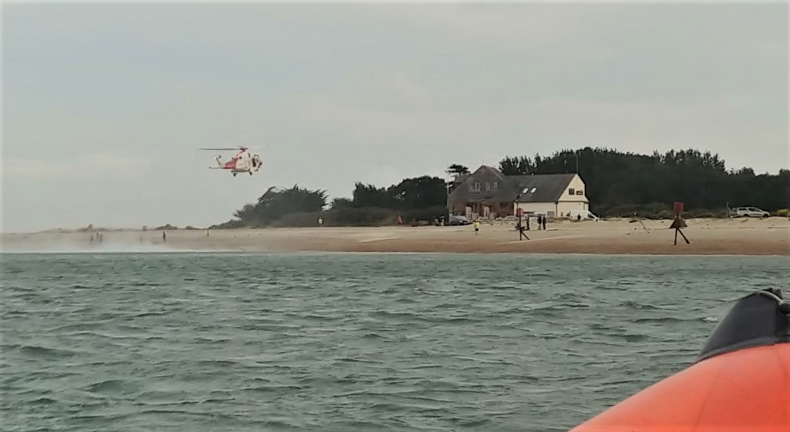 Wide photo showing the sea, lifeboat in the foreground and helicopter about to land by Hayling lifeboat station.