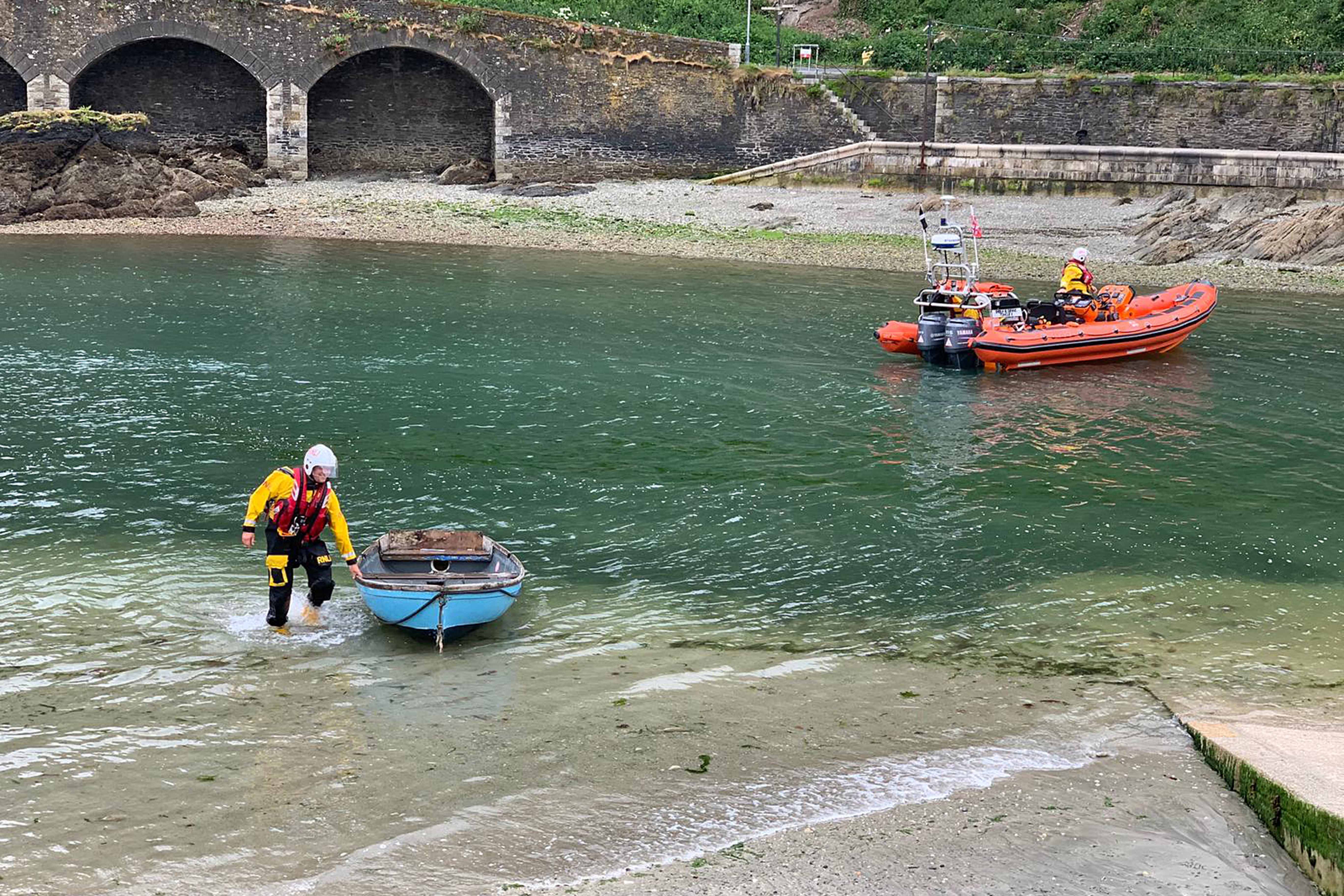 Looe RNLI volunteer crew Jack Spree bring the dinghy ashore at Looe lifeboat station