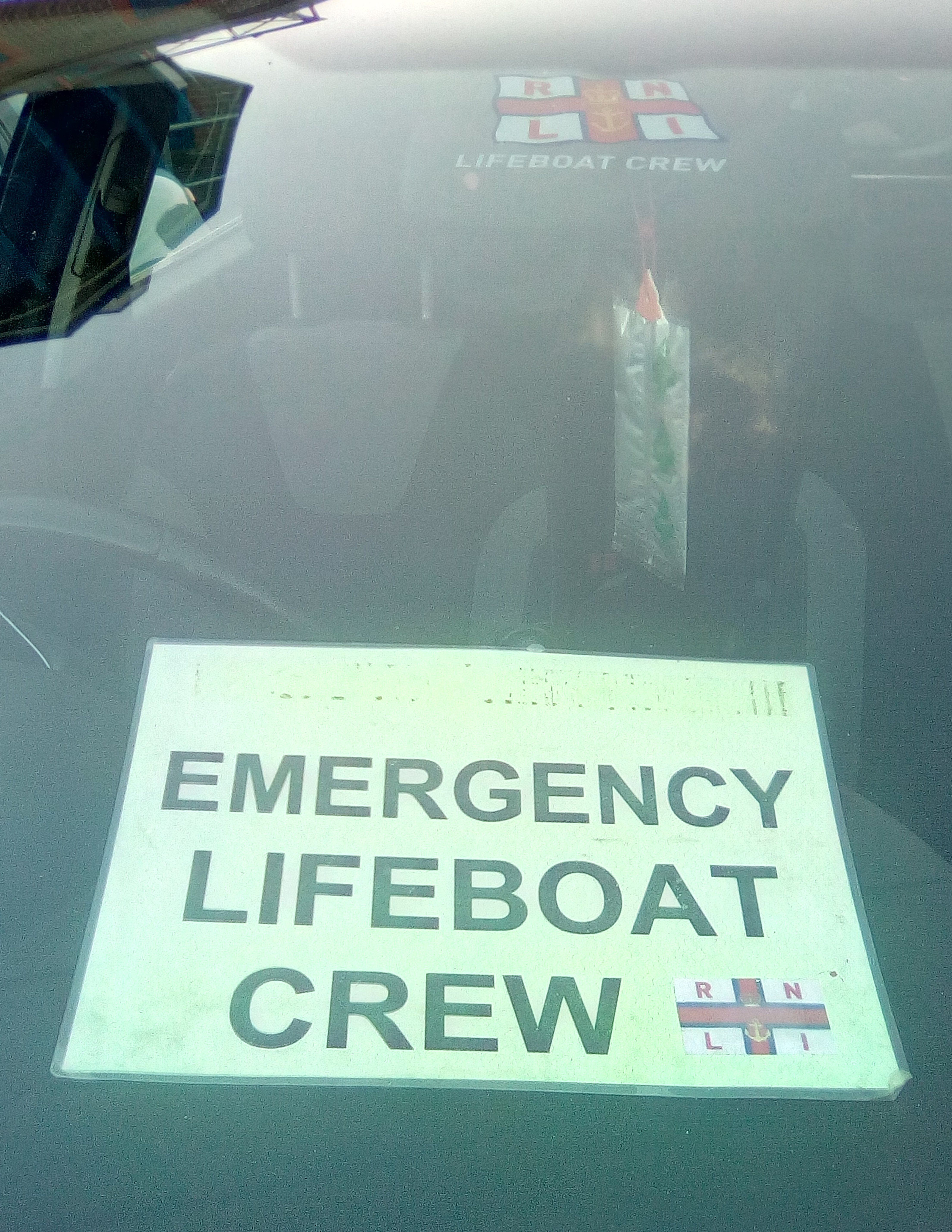 A card in a car window that says Emergency Lifeboat Crew