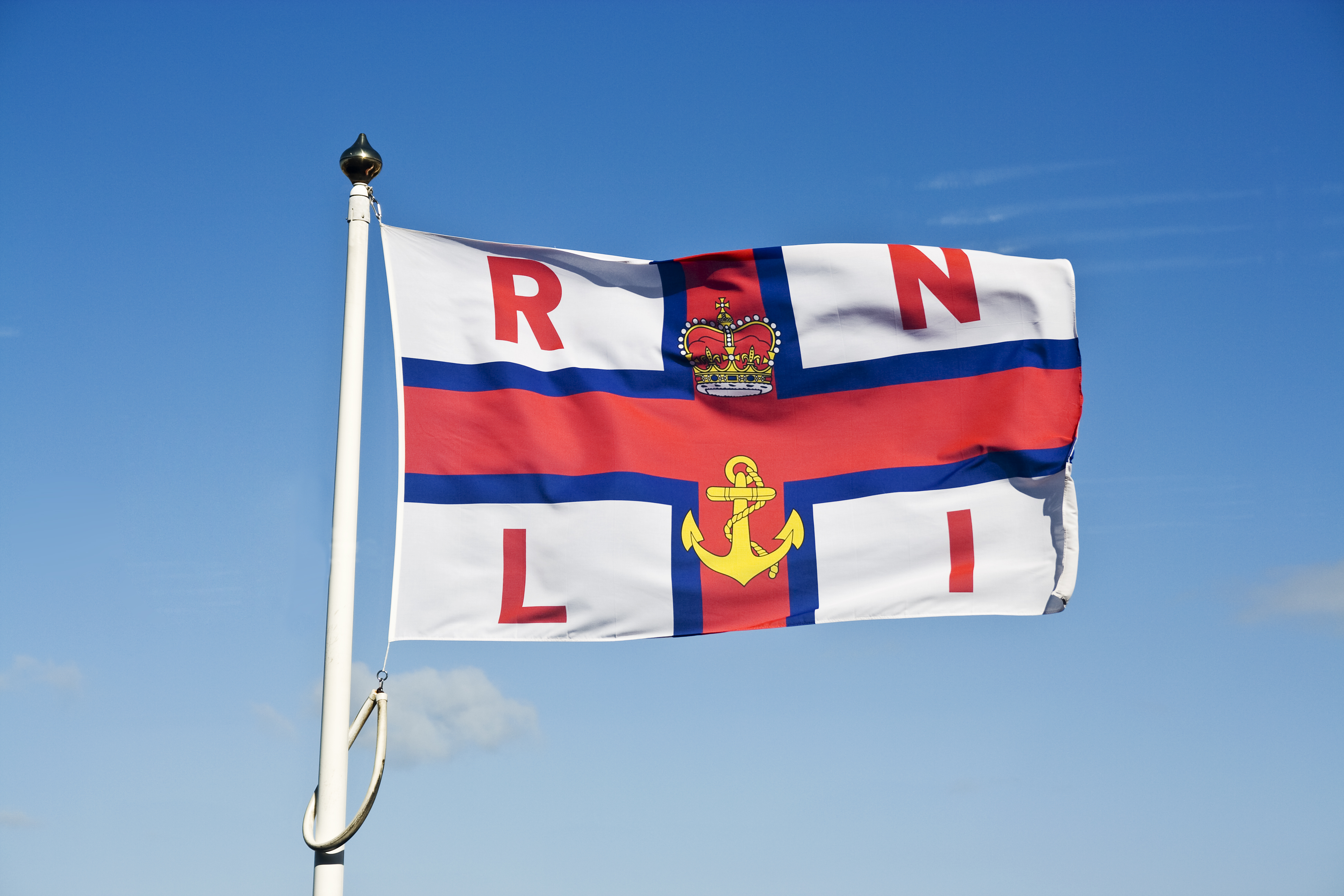 RNLI flag flying with blue sky behind it