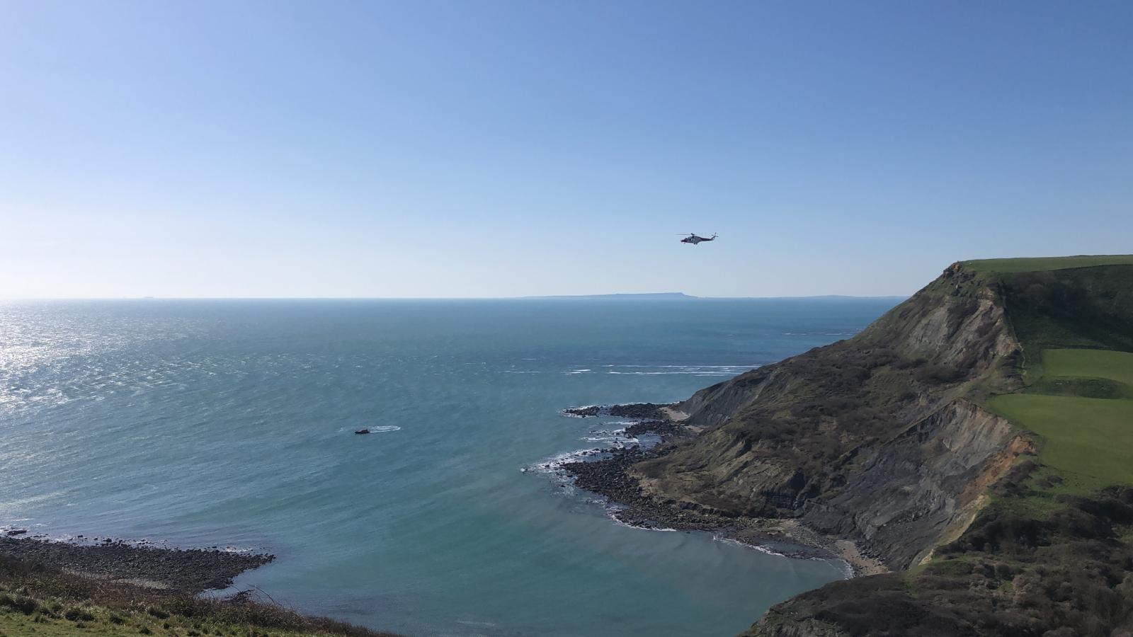 Picture taken from land showing HM Coastguard hovering over Chapman's Pool, with Swanage all-weather lifeboat in the bay.