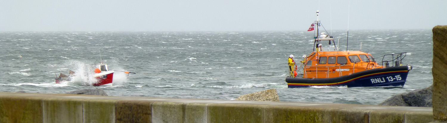 The fishing coble is towed past the east pier