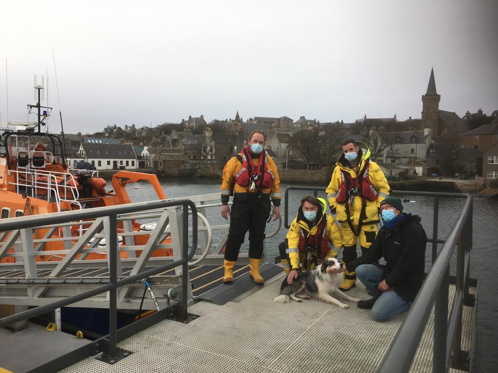 Three crew members wearing covid masks plus owner and dog on Stromness pier