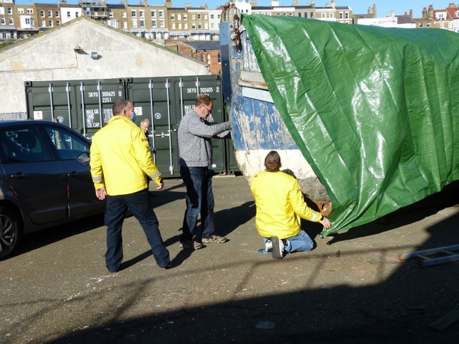 Pulling the protective covers over the historic lifeboat.