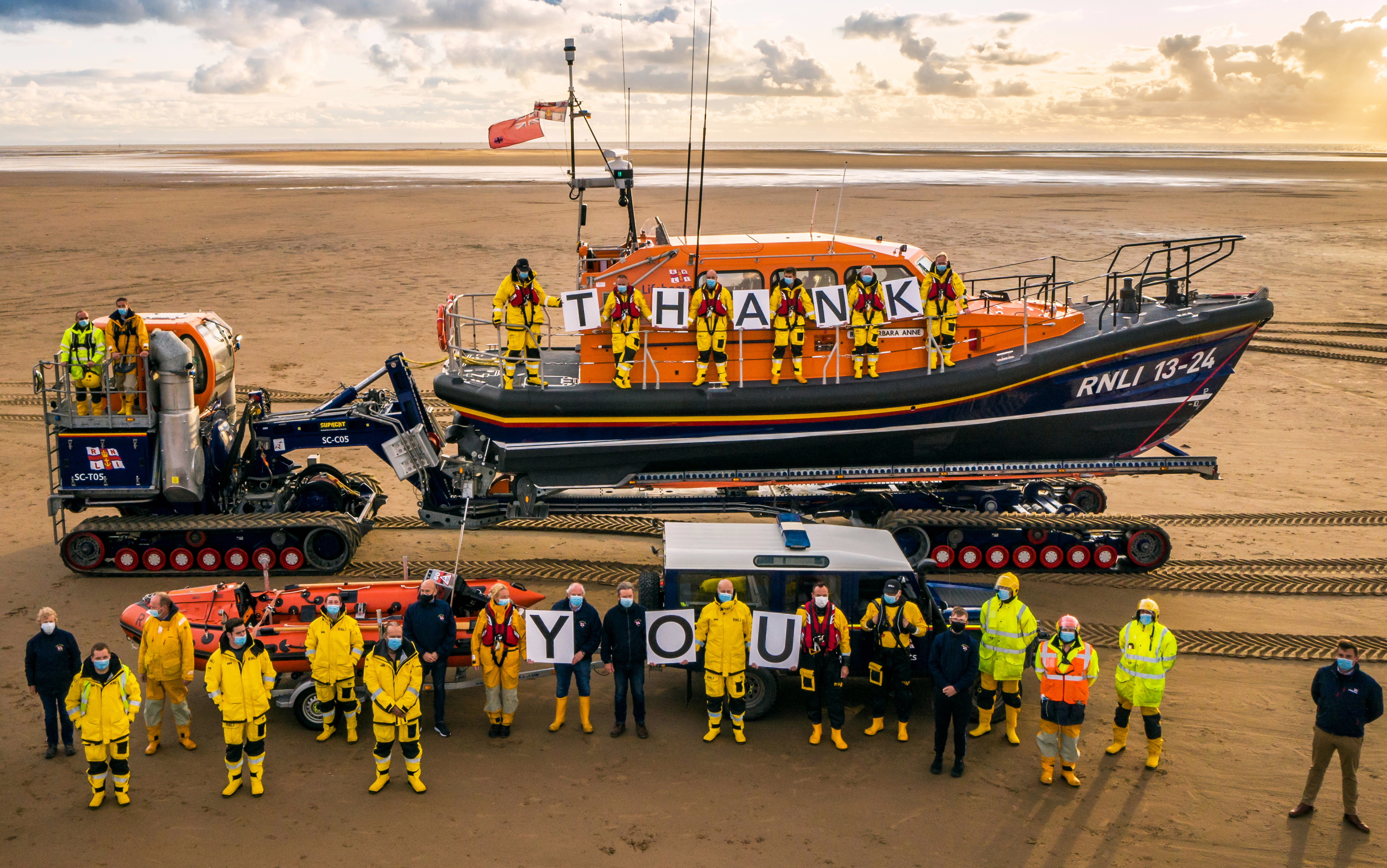 two lifeboats are surrounded by crew members holding up letters spelling "Thank You"