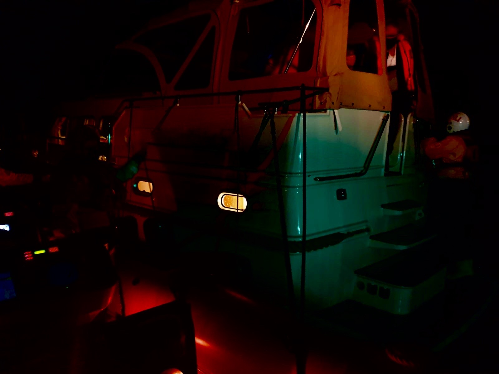 Lifeboat alongside casualty vessel, very dark, crew preparing a bridle for towing
