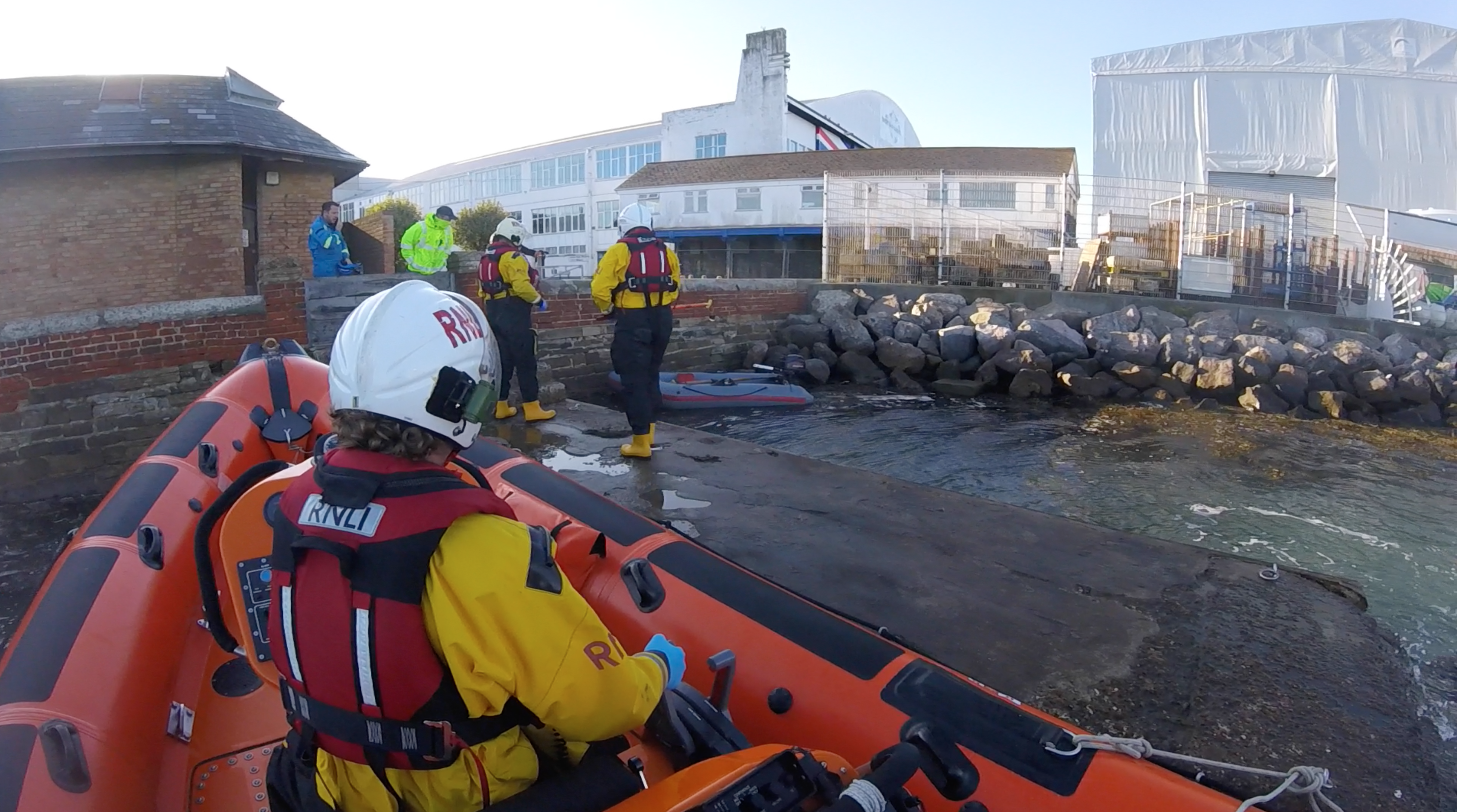 Lifeboat crew members disembark from lifeboat to examine the abandoned dinghy.