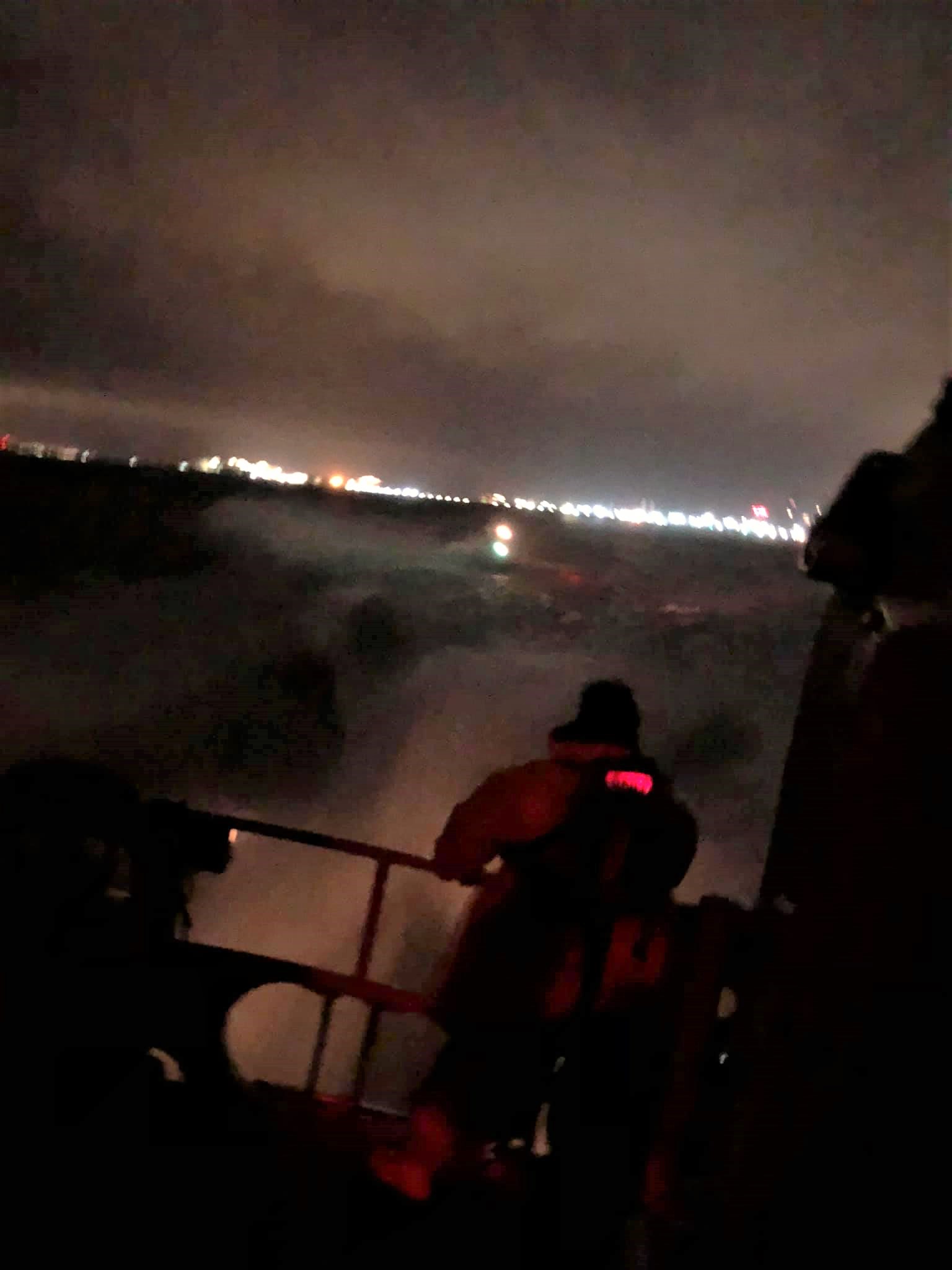 A crew member on the all-weather lifeboat keeping an eye on his friends in the inshore lifeboat that was tucked in behind to enable both boats to make best speed to rescue a man clinging to a mooring buoy