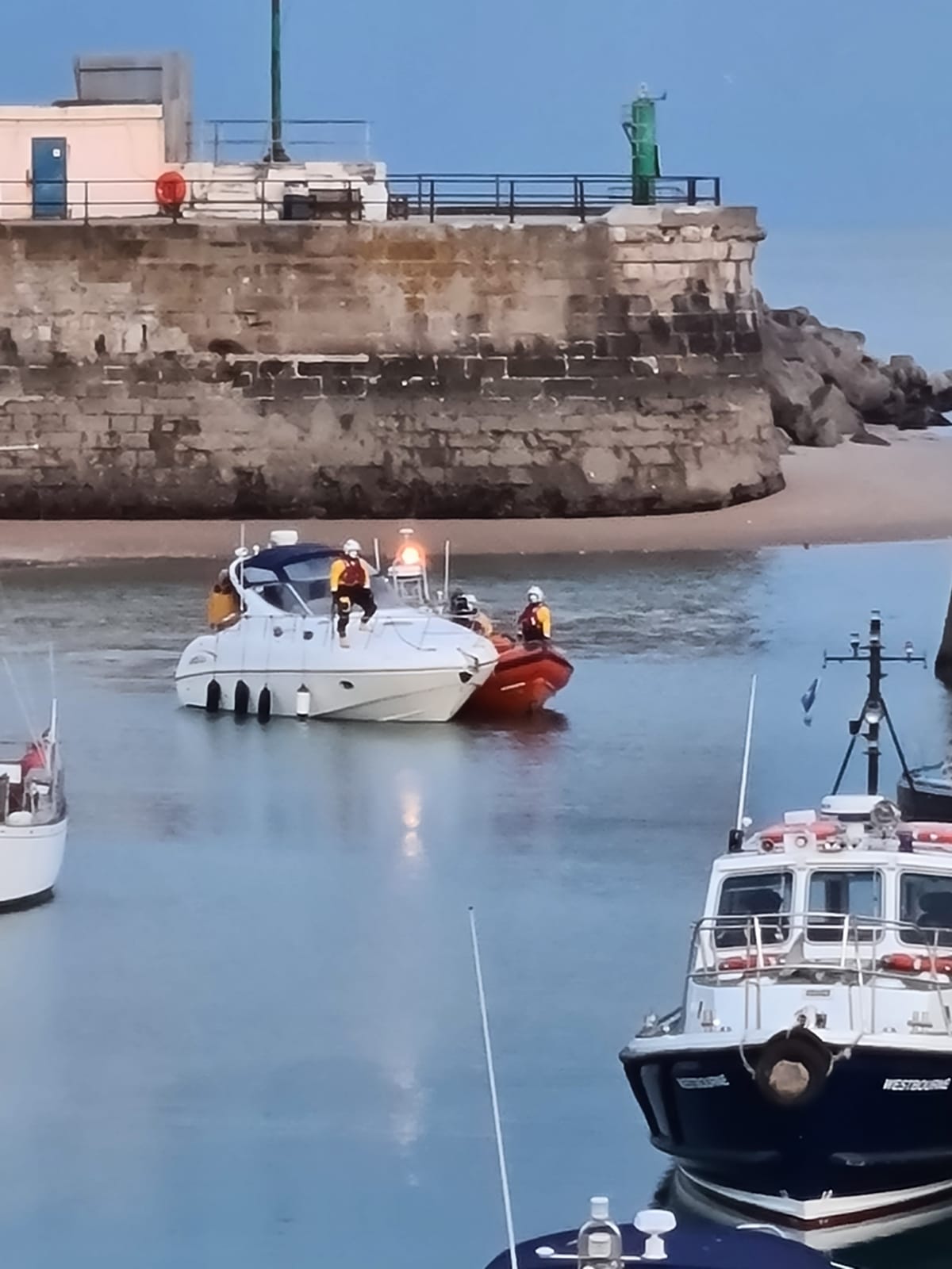 A lifeboat along side a small cabin cruiser.
