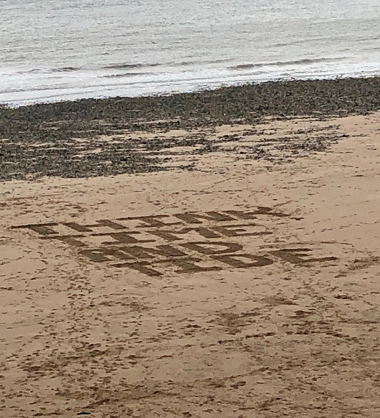 The words, Think Time and tide written in the sands.