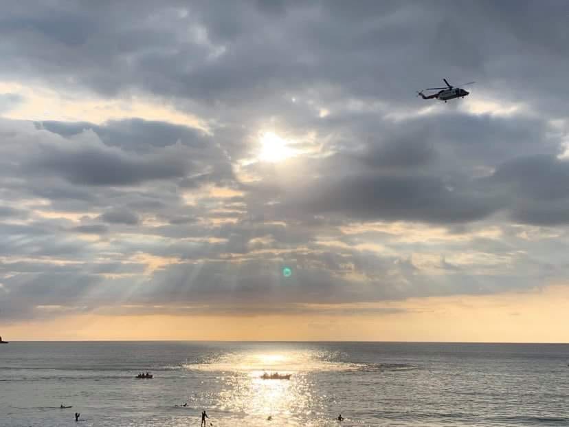 A panoramic view from Fistral Beach, with both lifeboat crews and Coastguard helicopter searching the foreground, in front of dramatic sky