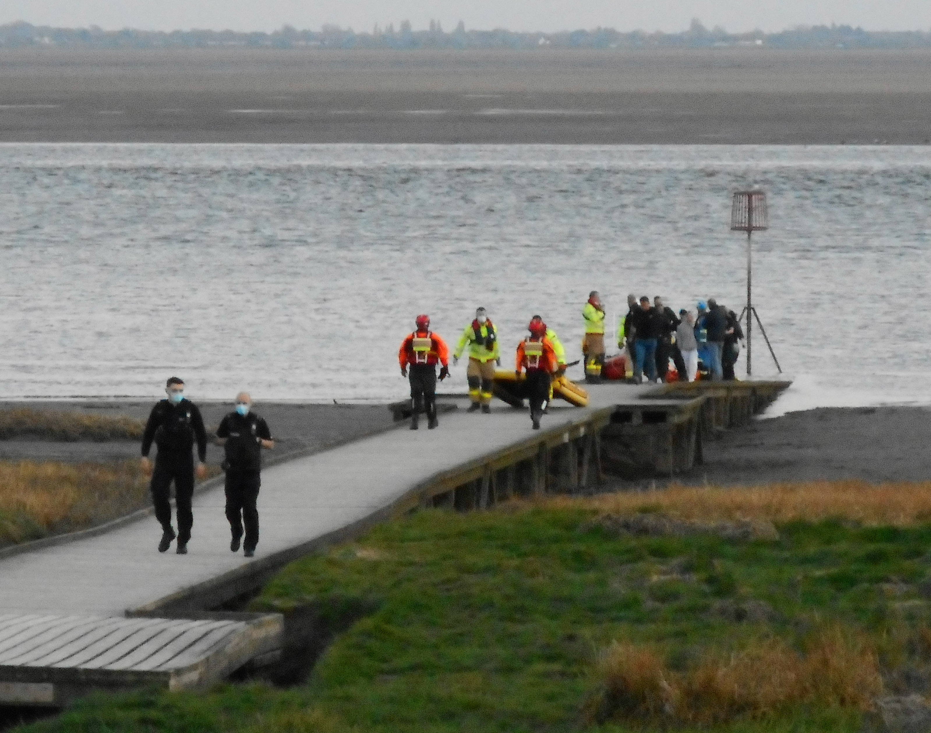 A group of people on a wooden jetty, the top of an ILB can be just seen on the other side
