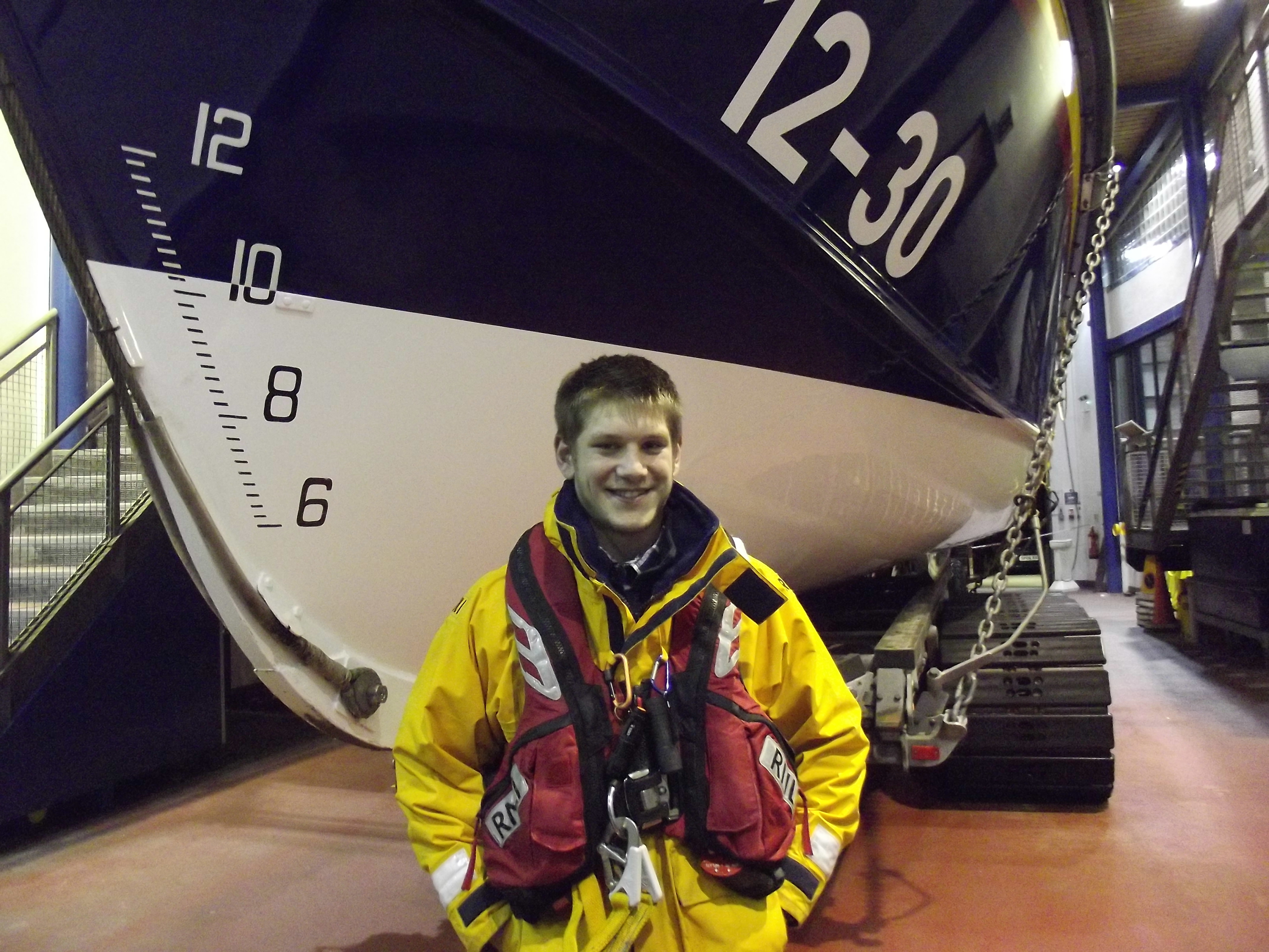 a crew member in full gear in front of a lifeboat's bow