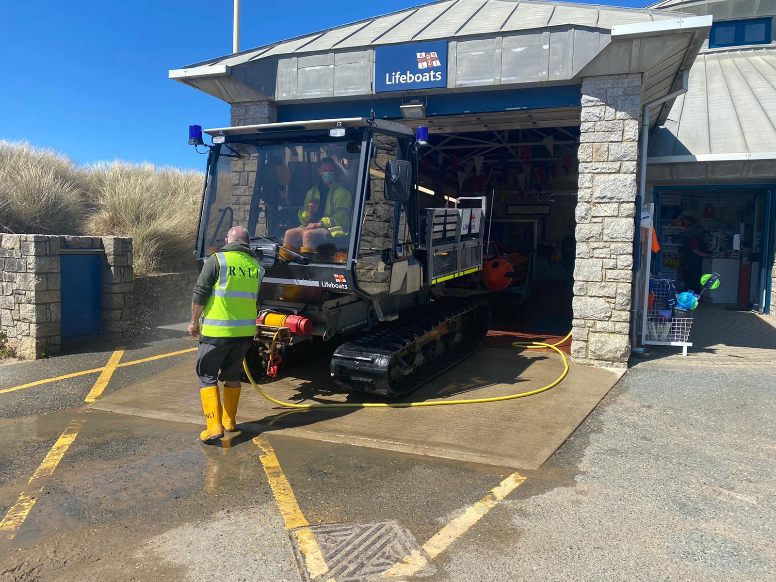 Bude RNLI shore crew hosing down the lifeboat and tractor in front of the lifeboat house so that they can be rehoused.