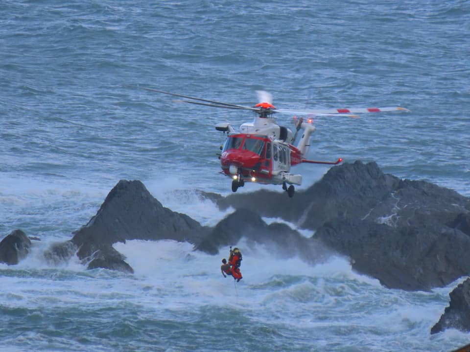 Coastguard helicopter winches casualty into helicopter over rough sea and breaking waves