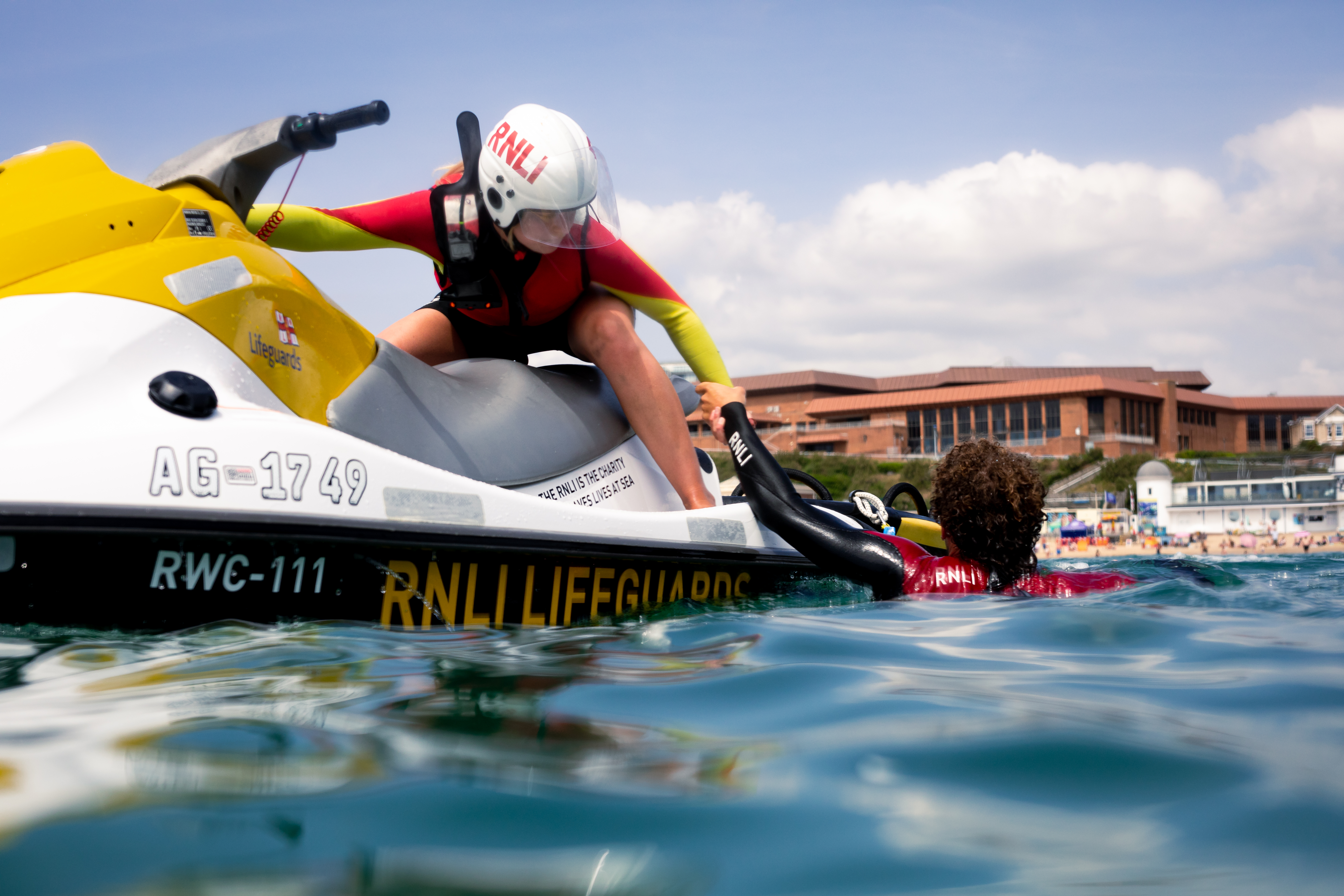 Lifeguard on water craft rescues another lifeguard as training