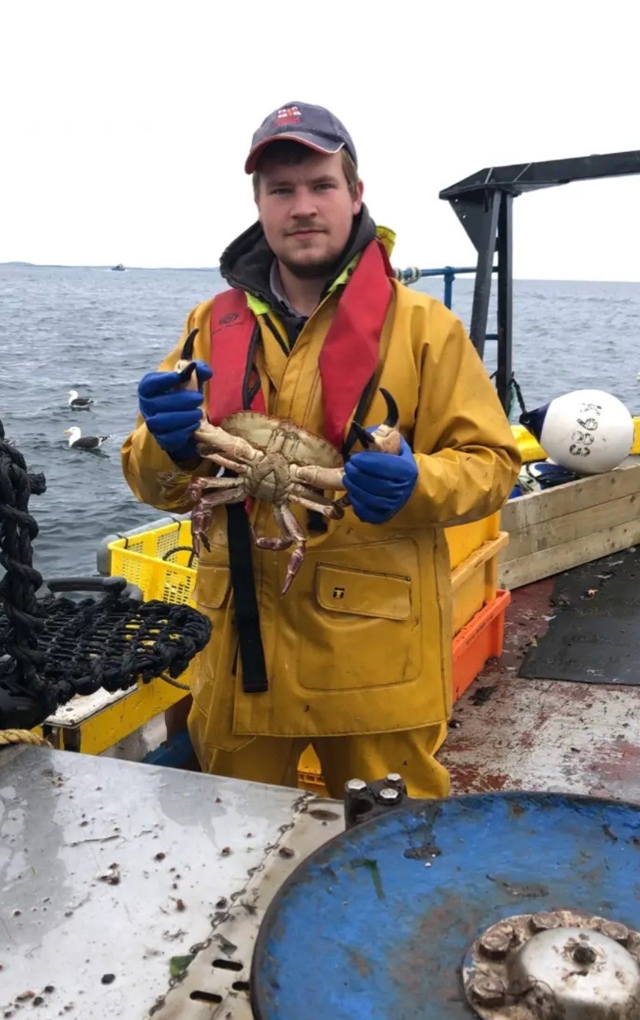 John holding a crab on a boat at sea