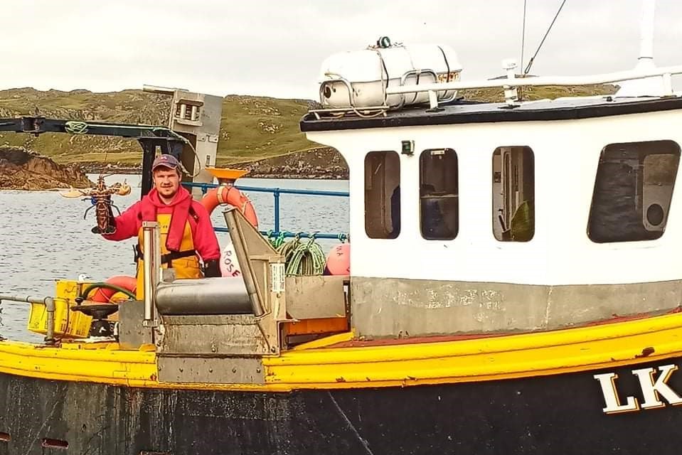 John Robertson on his new boat holding a lobster caught whilst at sea
