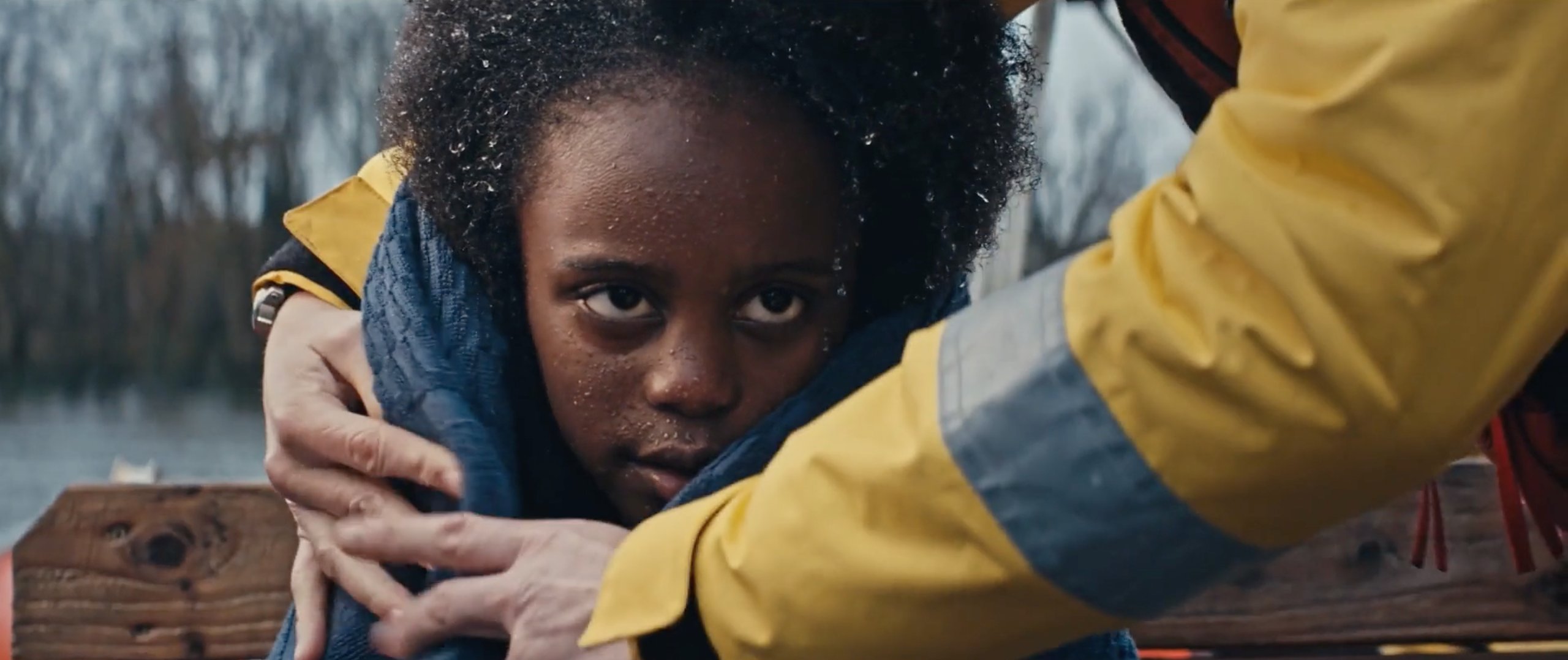 Crew member holding a blanket around a young girl