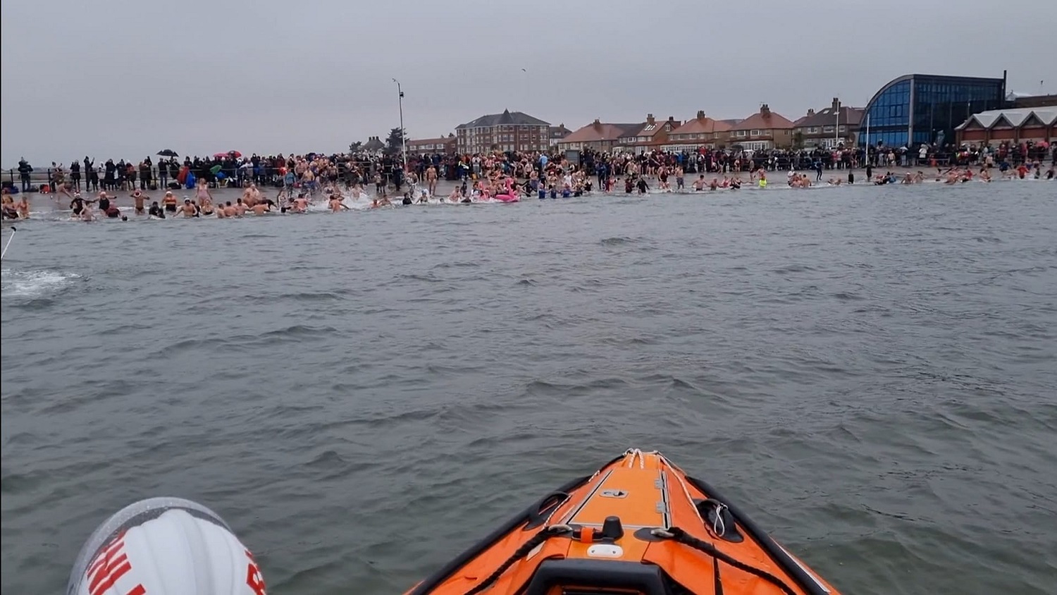 View of a shoreline with people swimming from an orange boat.