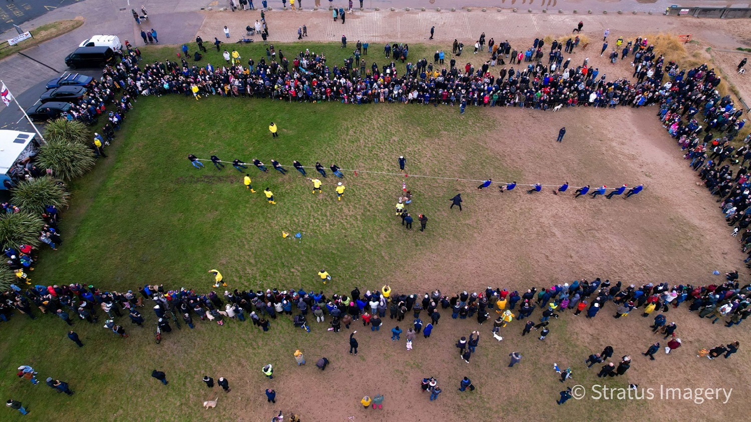 Aerial footage of a tug of war event on a green and brown playing field