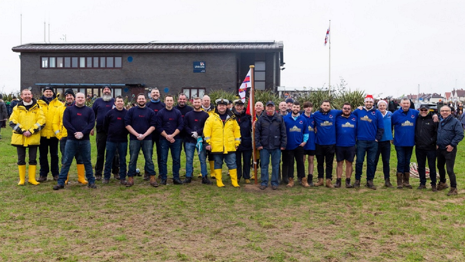A large group of people stand in a field and smile for a photo.
