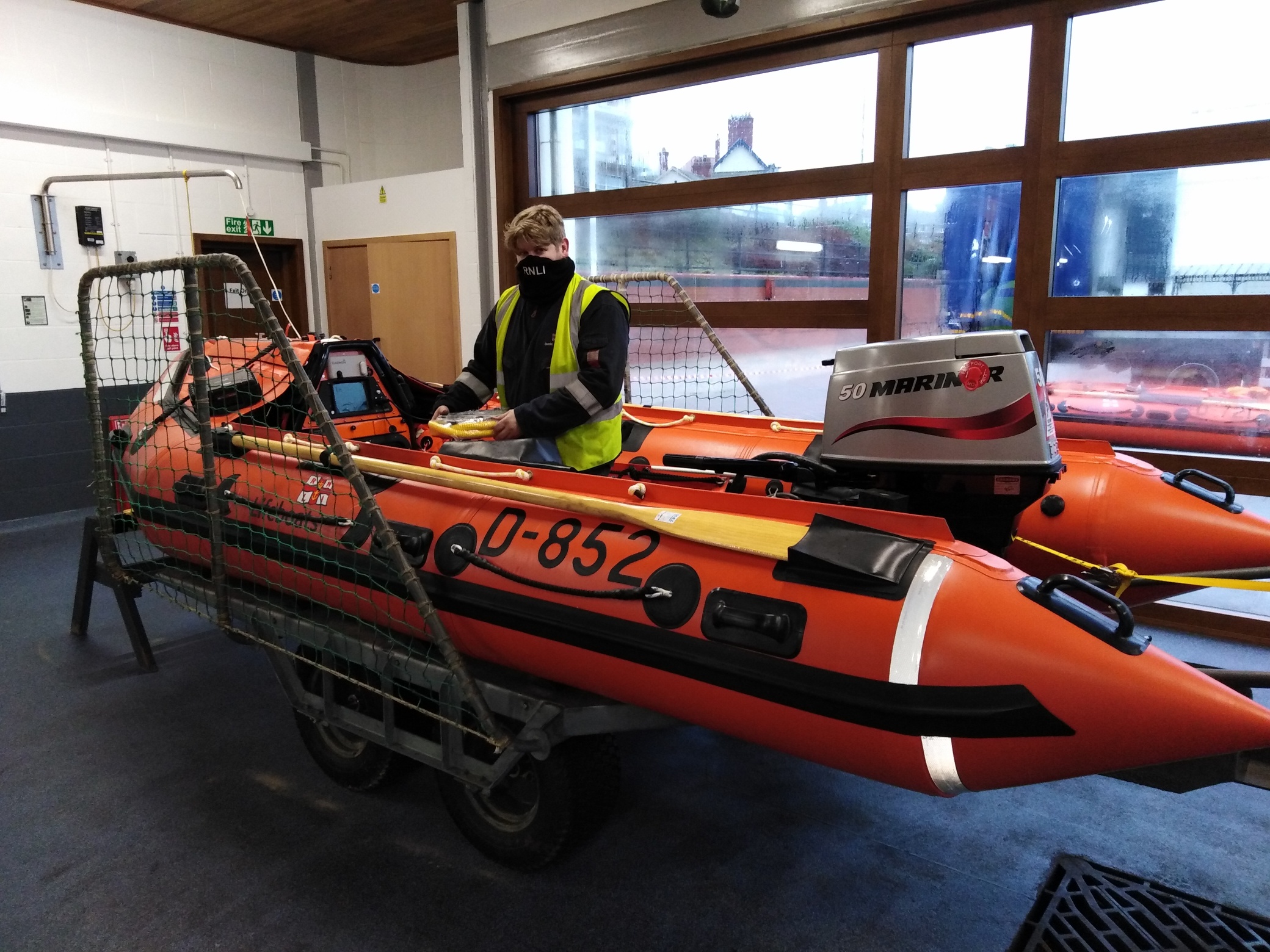 A man is checking an inshore lifeboat when it is inside Bridlington's boathouse