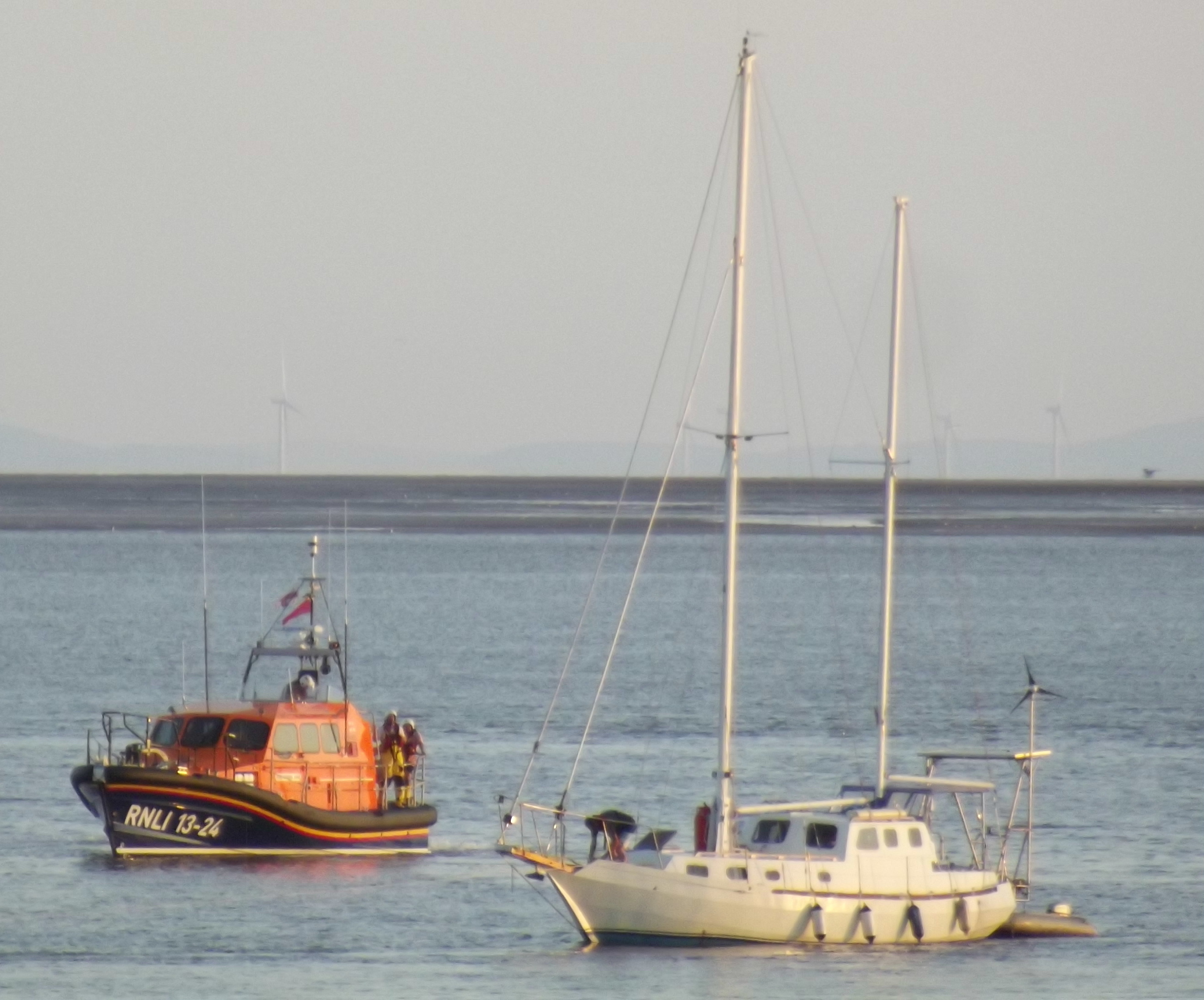 a Lifeboat is standing off a large ketch.