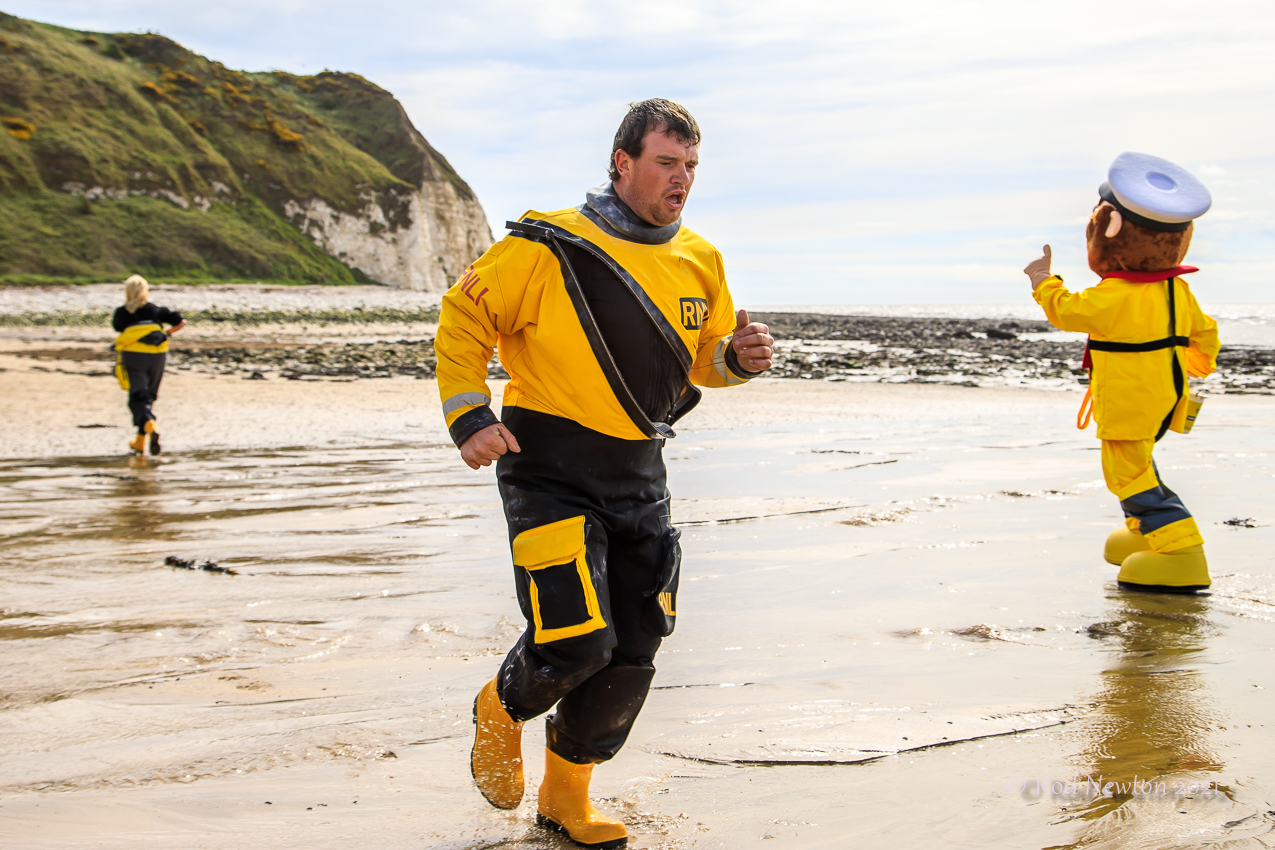 Crew member in full kit jogging on the beach with encouragement from Stormy Stan.