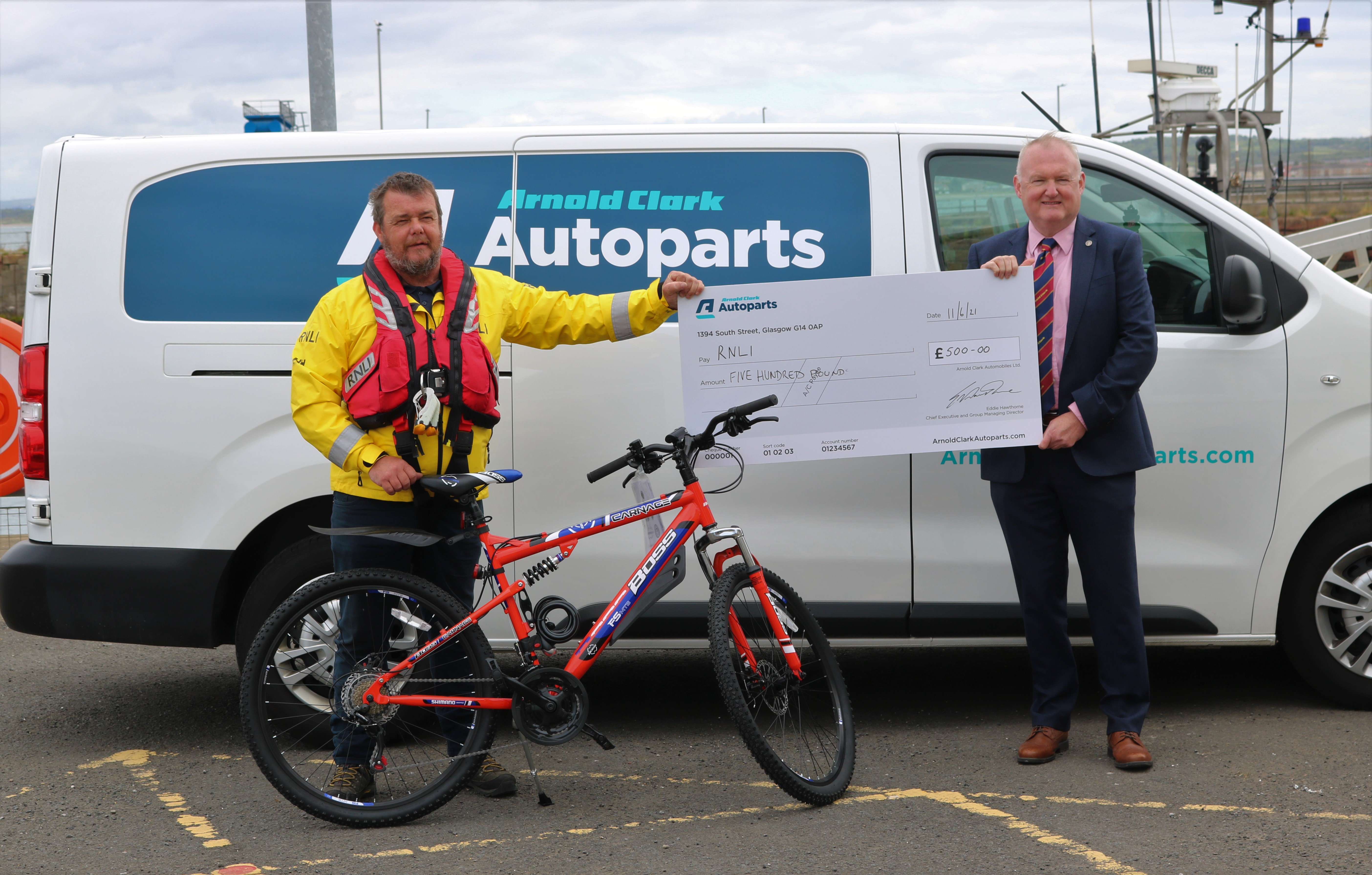 Evan Gallacher with his new bike being presented with the £500 donation by Craig McCracken, Group Factor Manager at Arnold Clark Autoparts