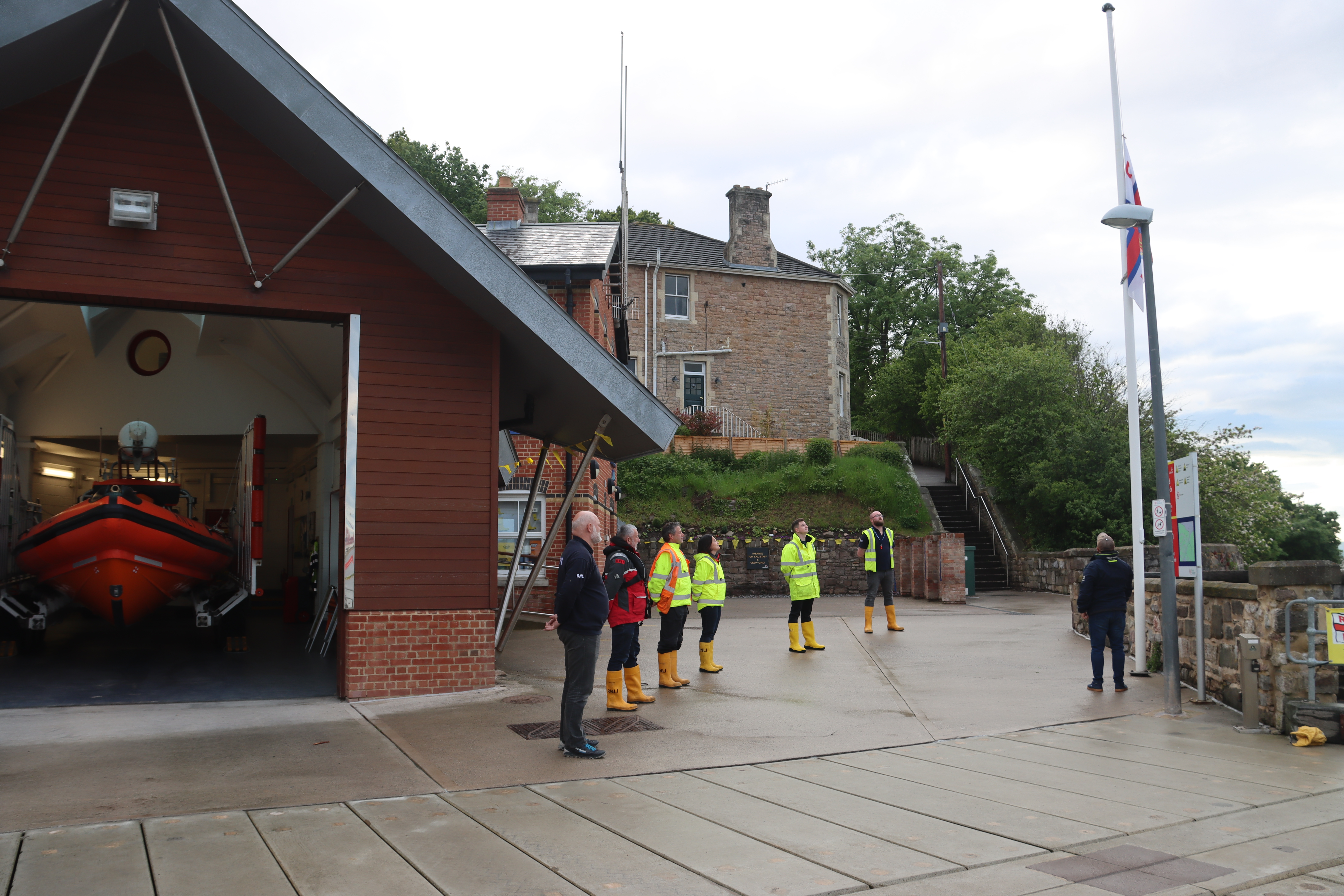 Crew volunteers stand with the flag at half mast in honour of Peter