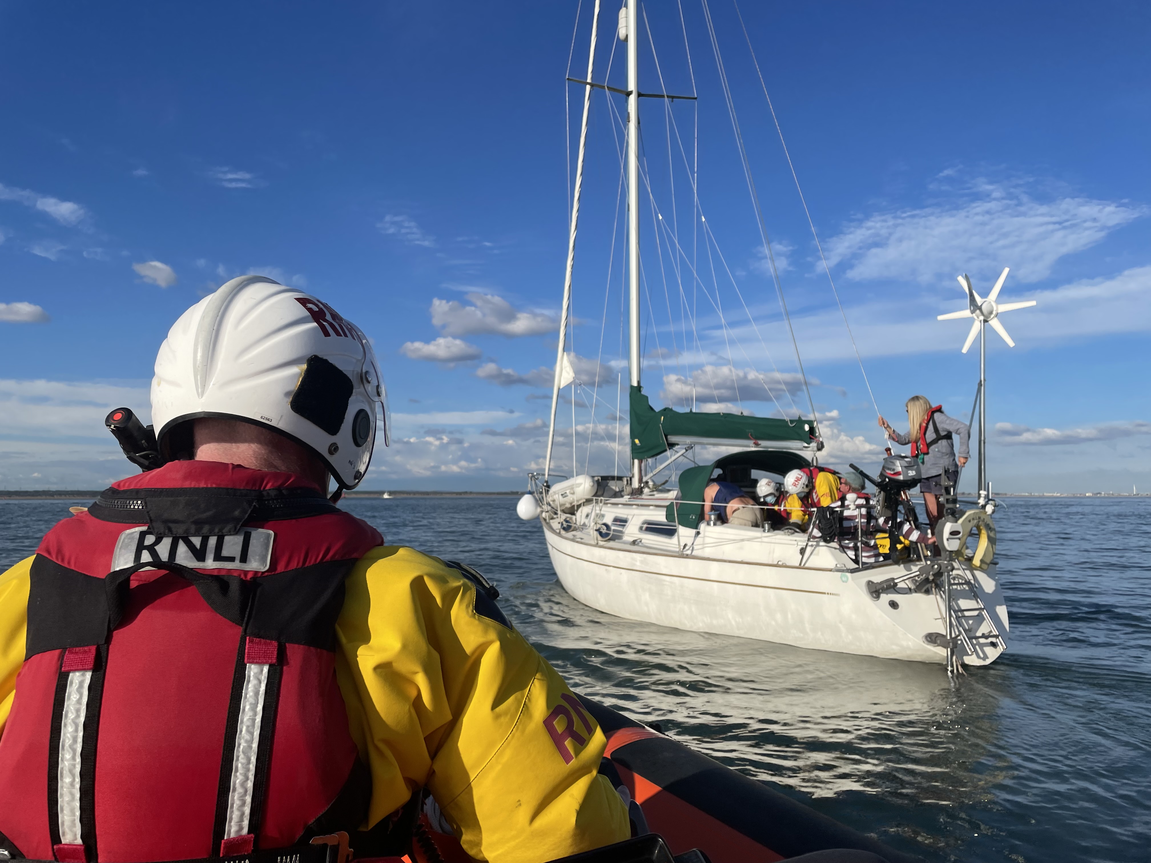 Lifeboat crew member watches from lifeboat as fellow crew members tackle the leak aboard the yacht.