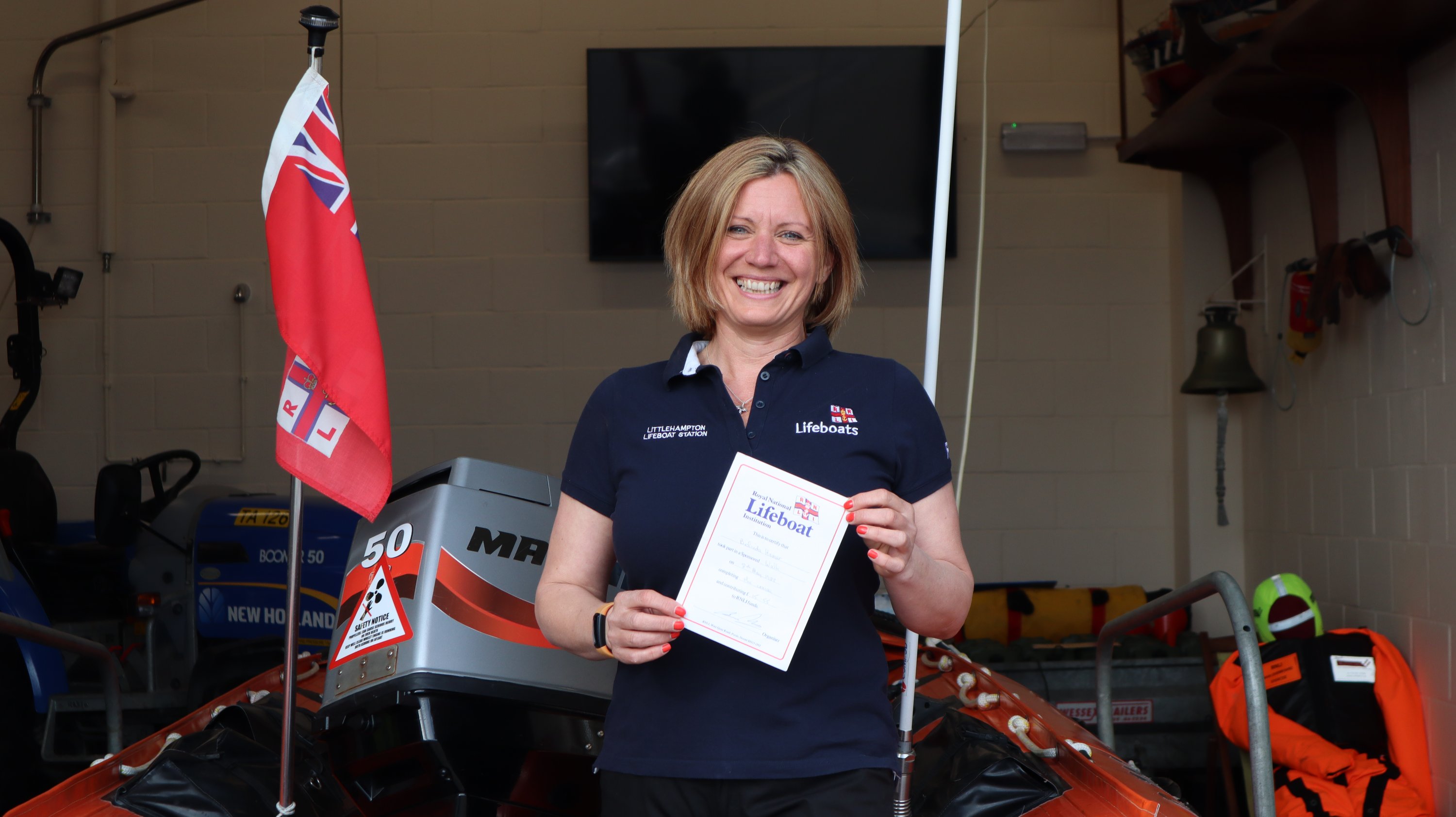Bea Homer proudly holds her fundraising certificate from 1988 in front of one of Littlehampton's lifeboats