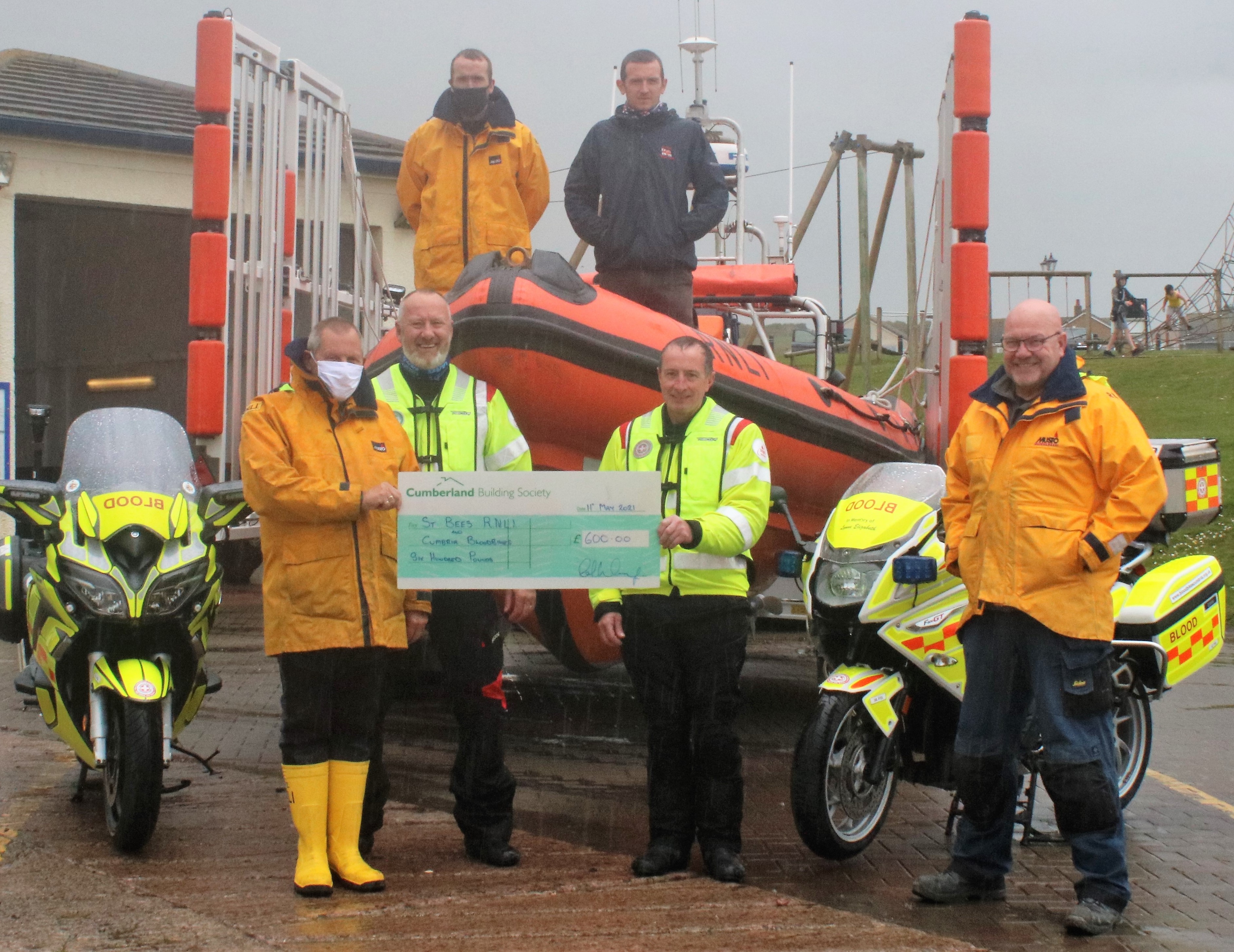 RNLI volunteers receiving the cheque from Dave Rothery and Rob Fisher from Blood Bikes Cumbria.