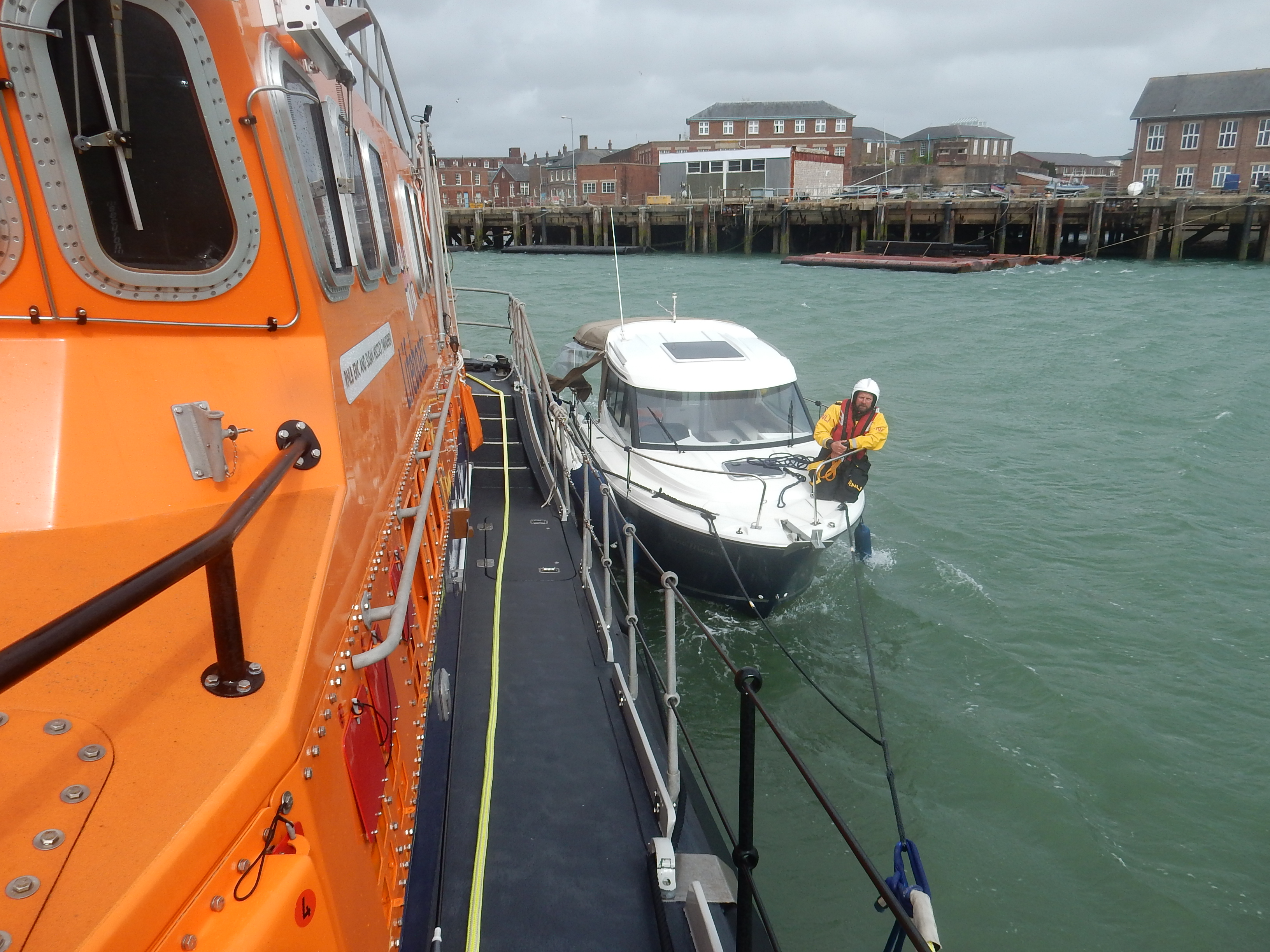 Yarmouth RNLI all weather lifeboat bringing the motor boat safely in Portsmouth Harbour