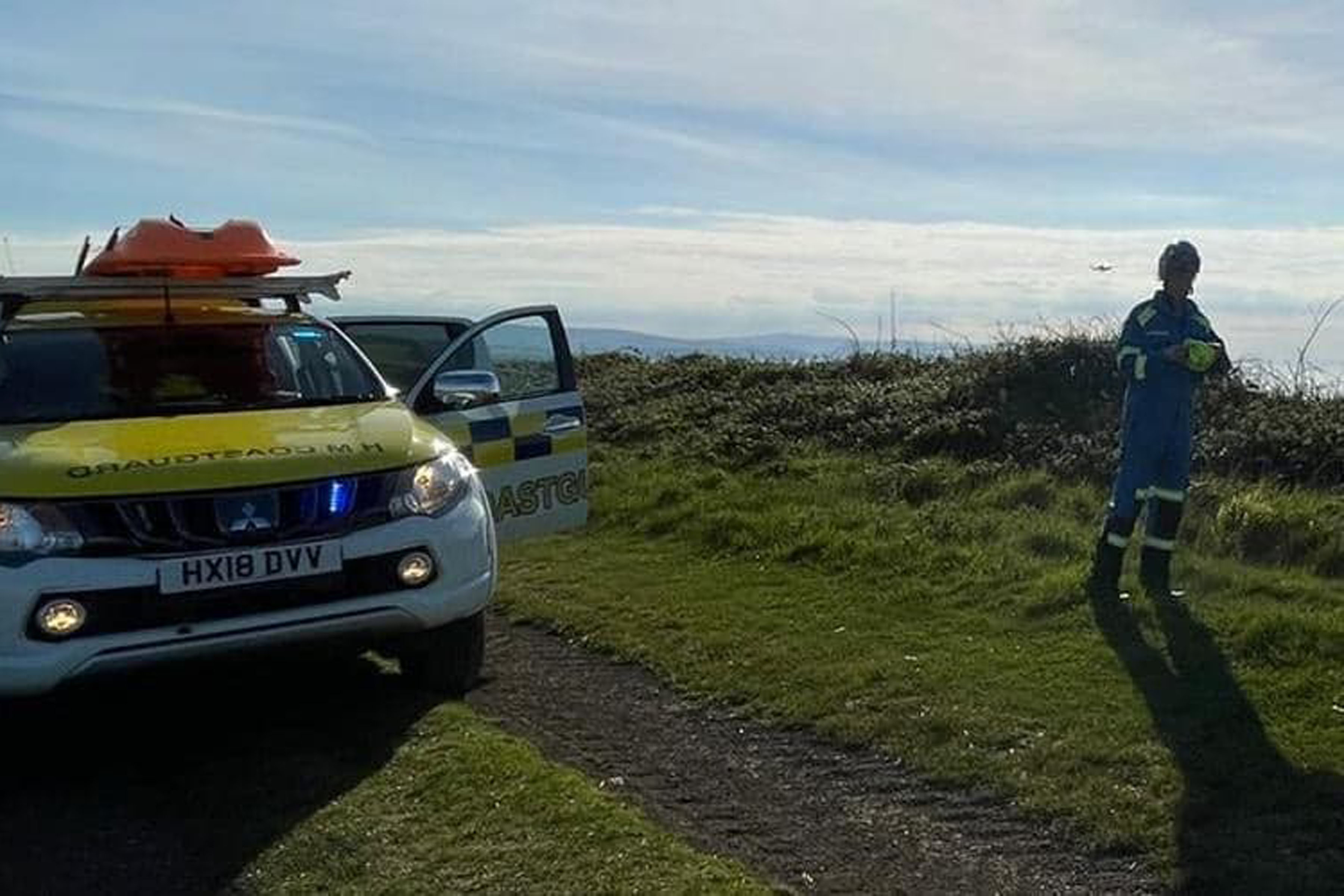 HM coastguard on the cliif edge surveys the scene