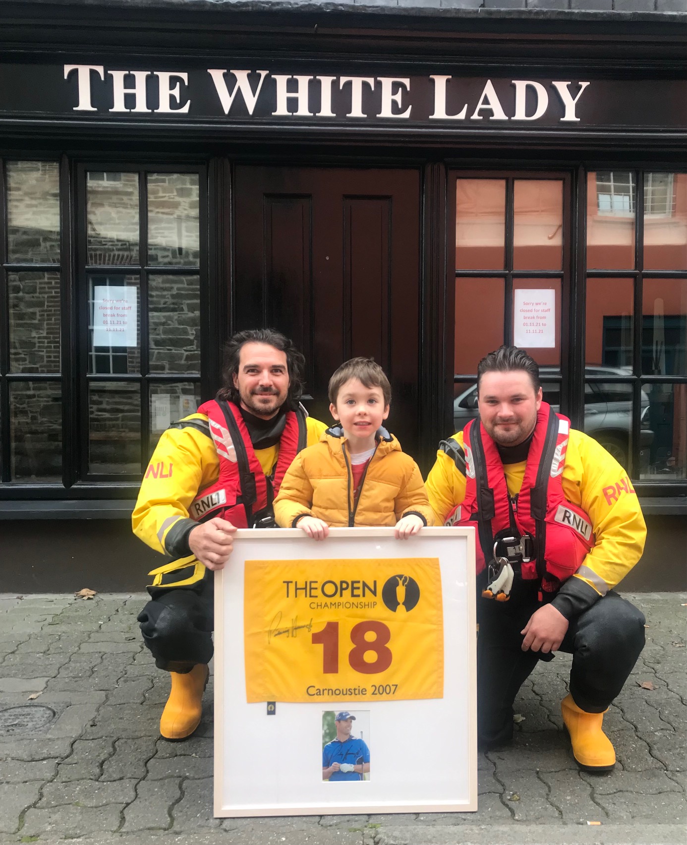 RNLI volunteers Mark Cotter and Jonathan Connor present 4 year old Tomás Quigley with his prize from the White Lady raffle that raised €2,415 for the RNLI