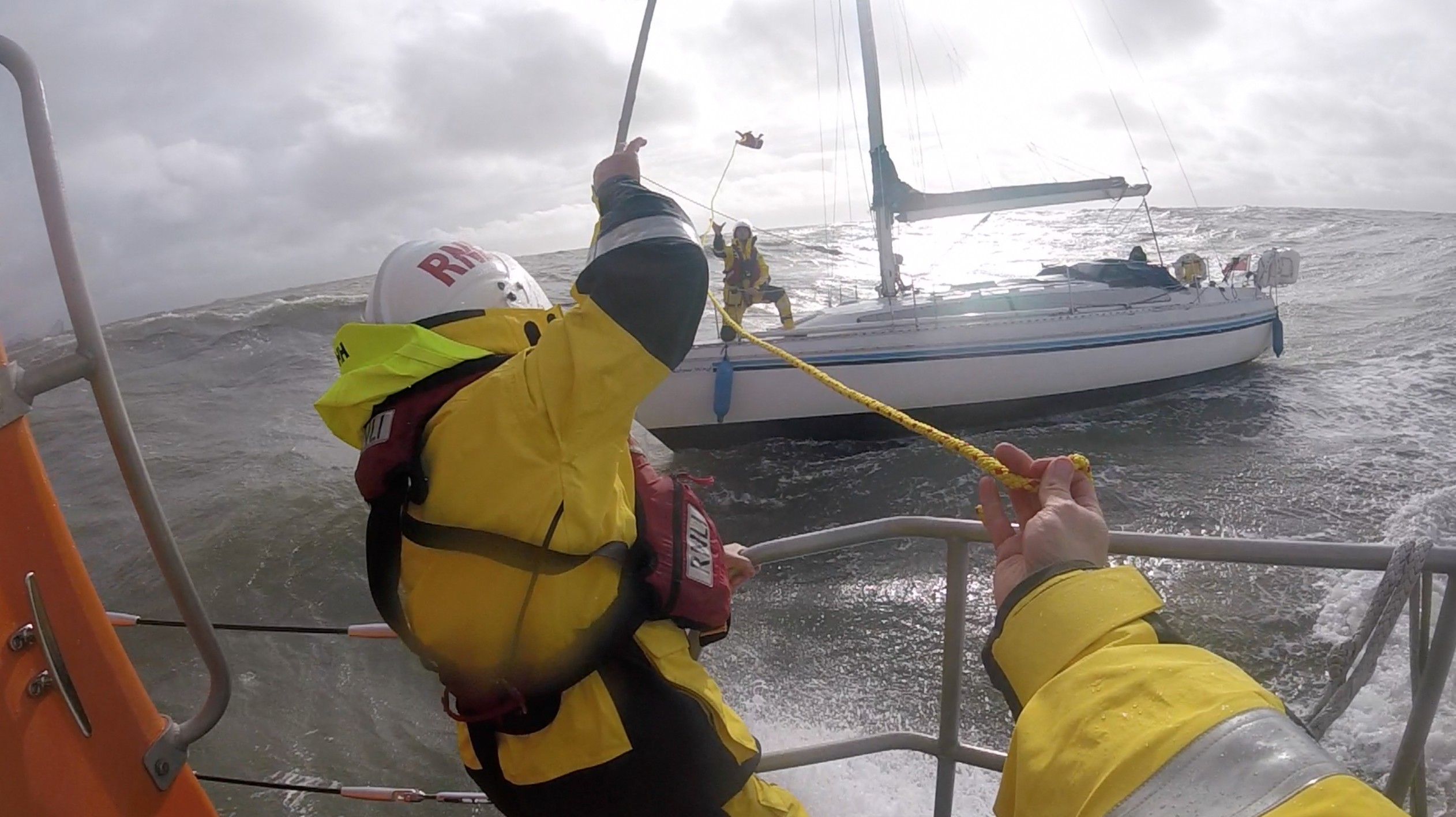 A Lifeboat crew member throws a line across to a yacht
