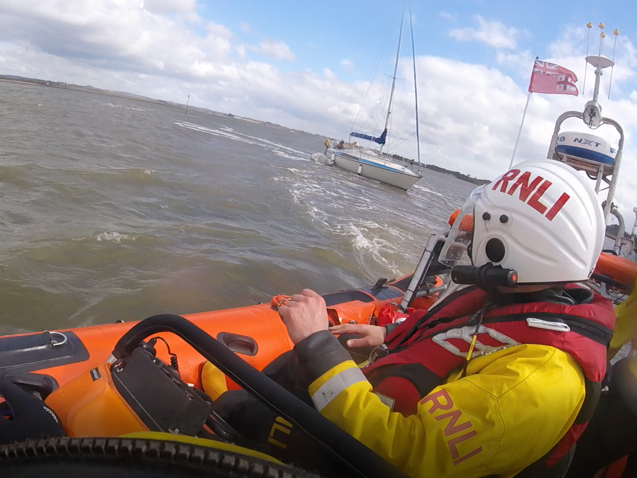 Yacht aground in the foreground Poole lifeboat volunteer looking across 