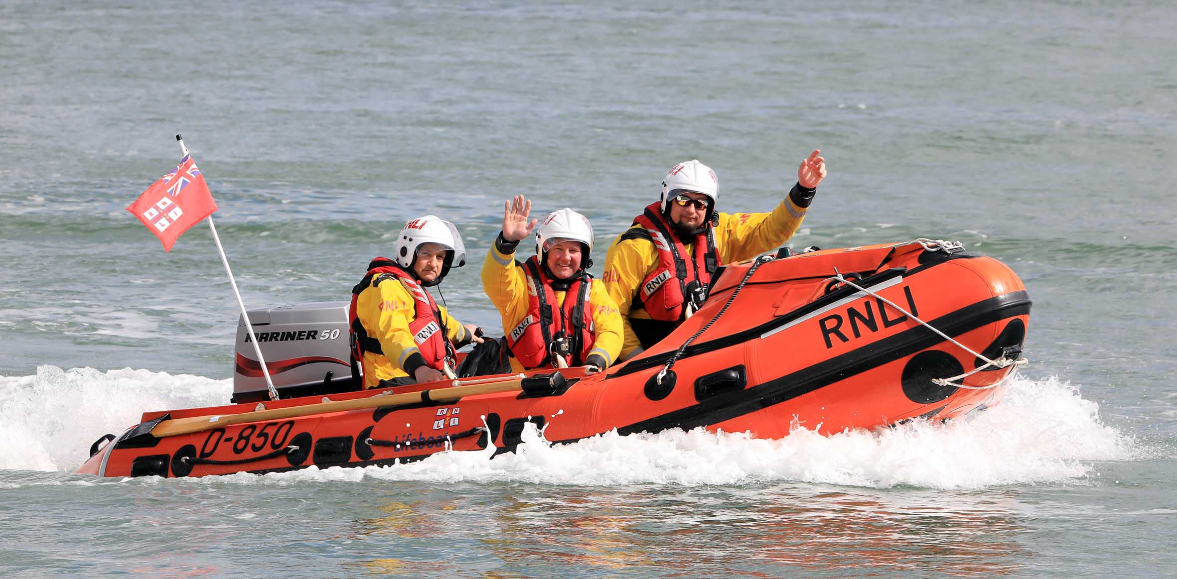 Photo of the new lifeboat at sea with crew waving to camera.