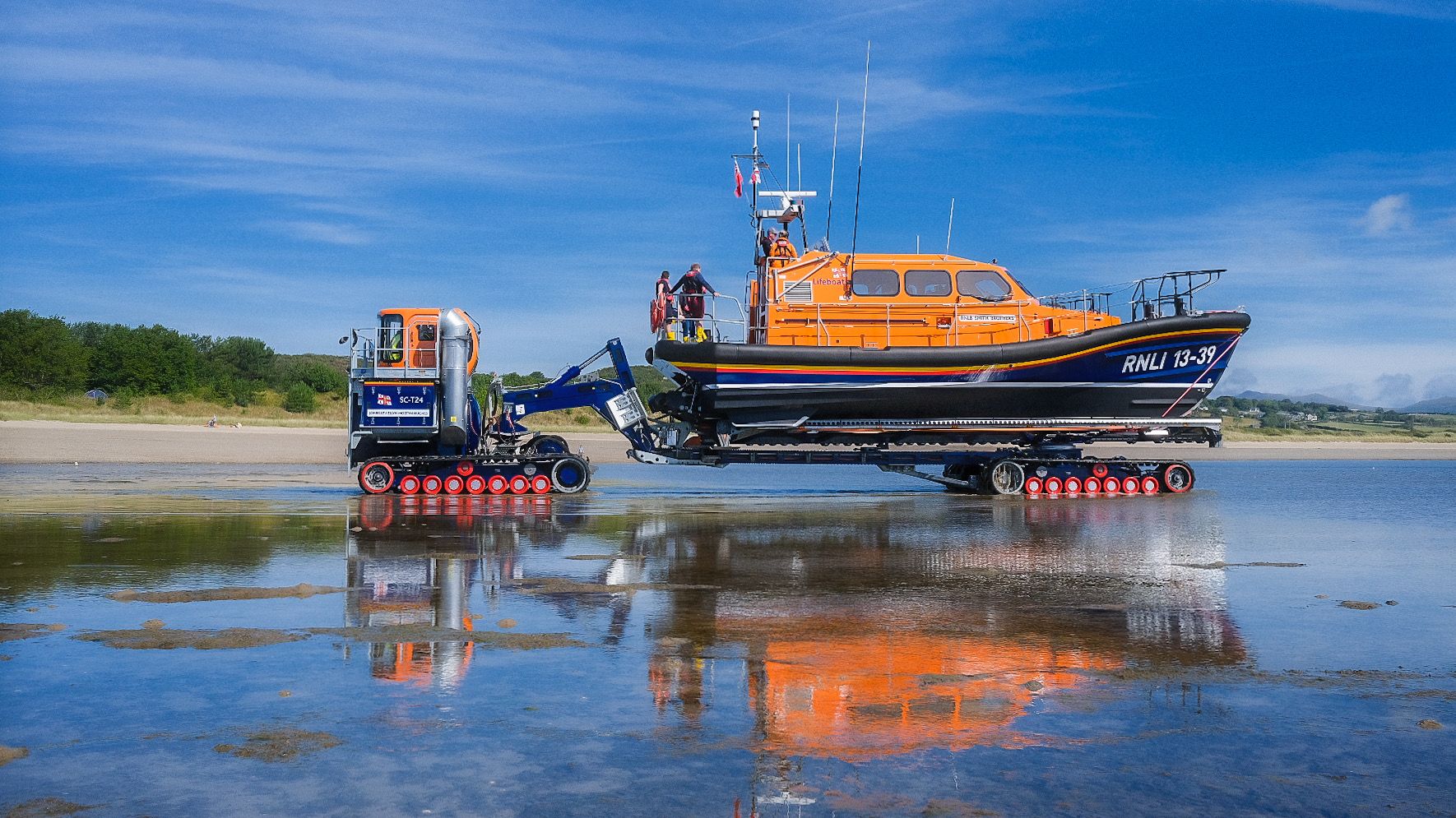 RNLI Pwllheli all-weather Shannon lifeboat launching on a sunny day with a blue sky