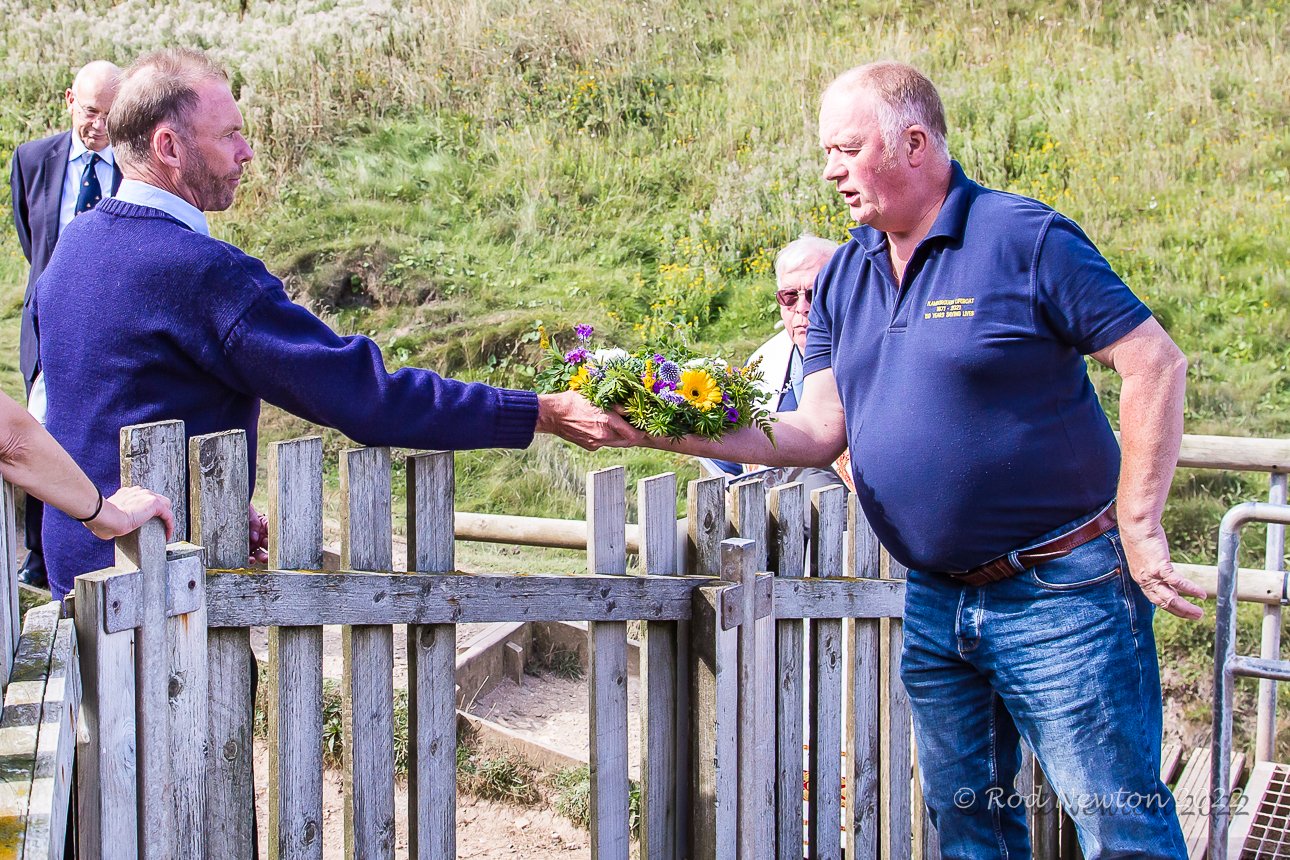 At Thornwick Bay, Bridlington RNLI Coxswain hands wreath to Flamborough RNLI.