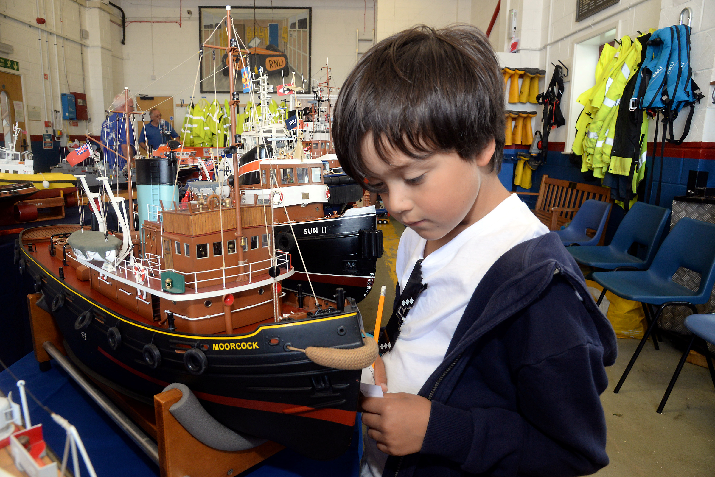 Emilio Abad, eight, inspects one of the model tugs on display at the Heron Model Boat Club show held in the Whitstable lifeboat station on Sunday.