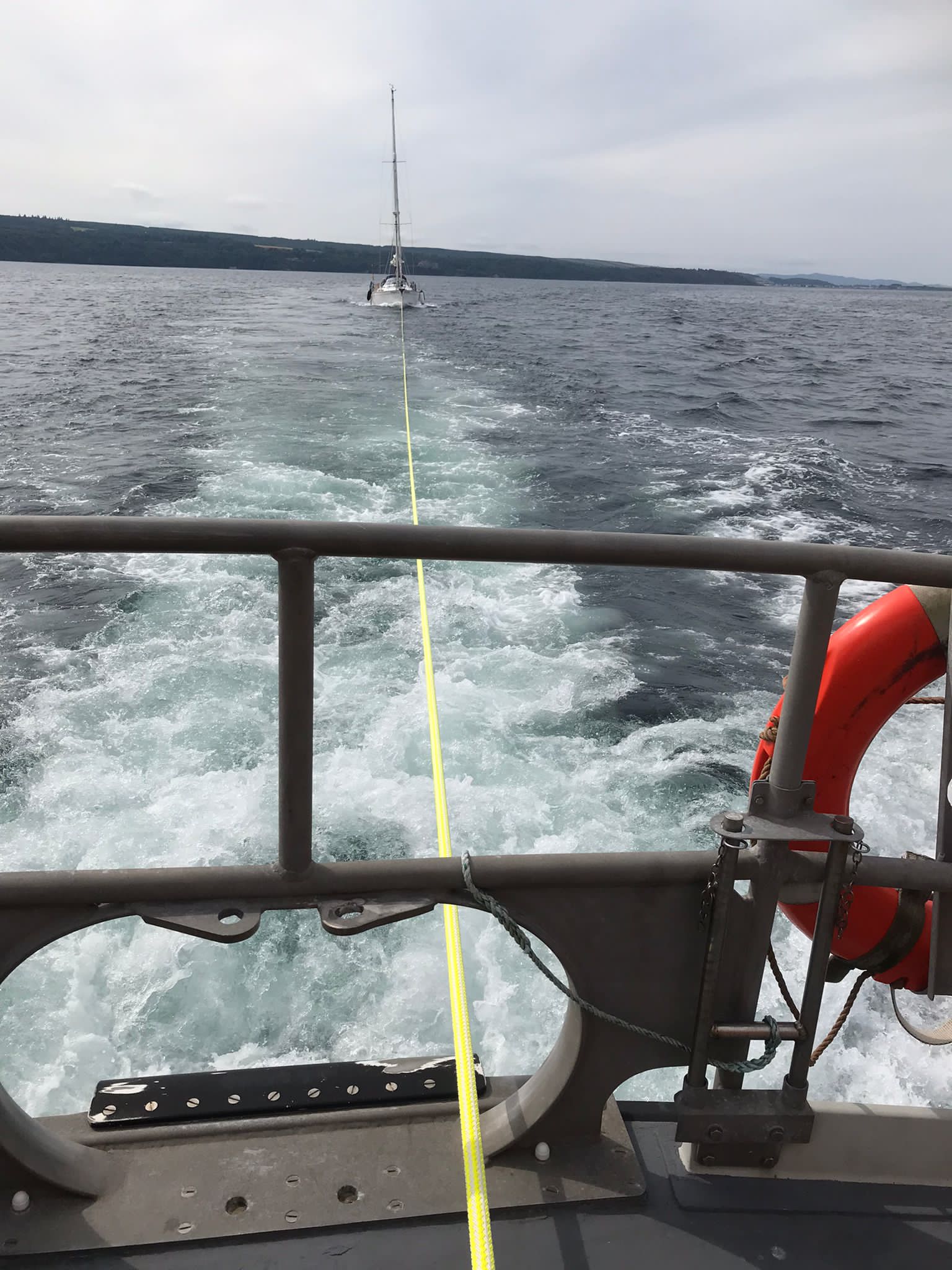 From the aft deck of the all-weather lifeboat, the tow line heads to the yacht on a calm sea