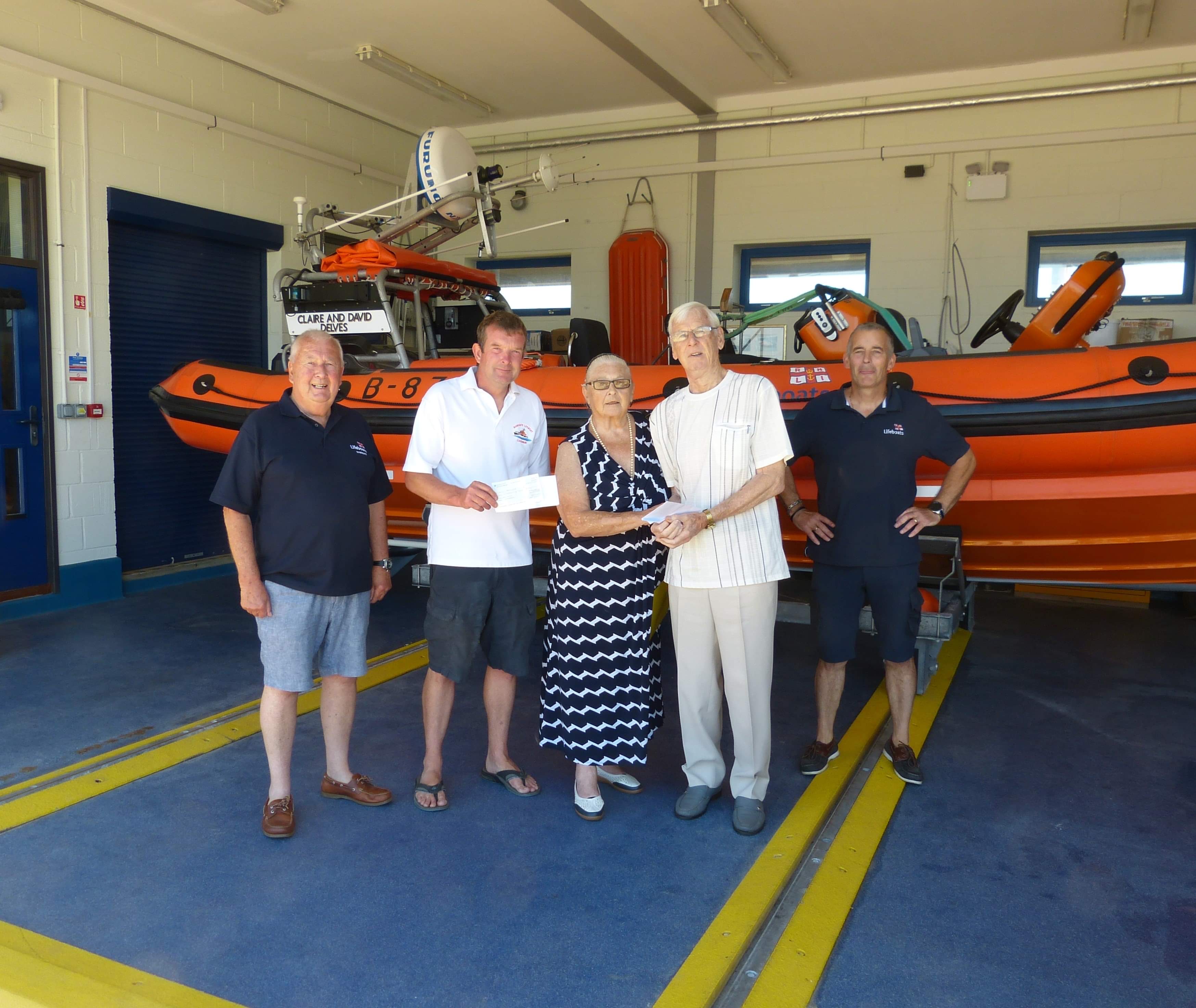 A group standing in front of the inshore lifeboat with a cheque. 